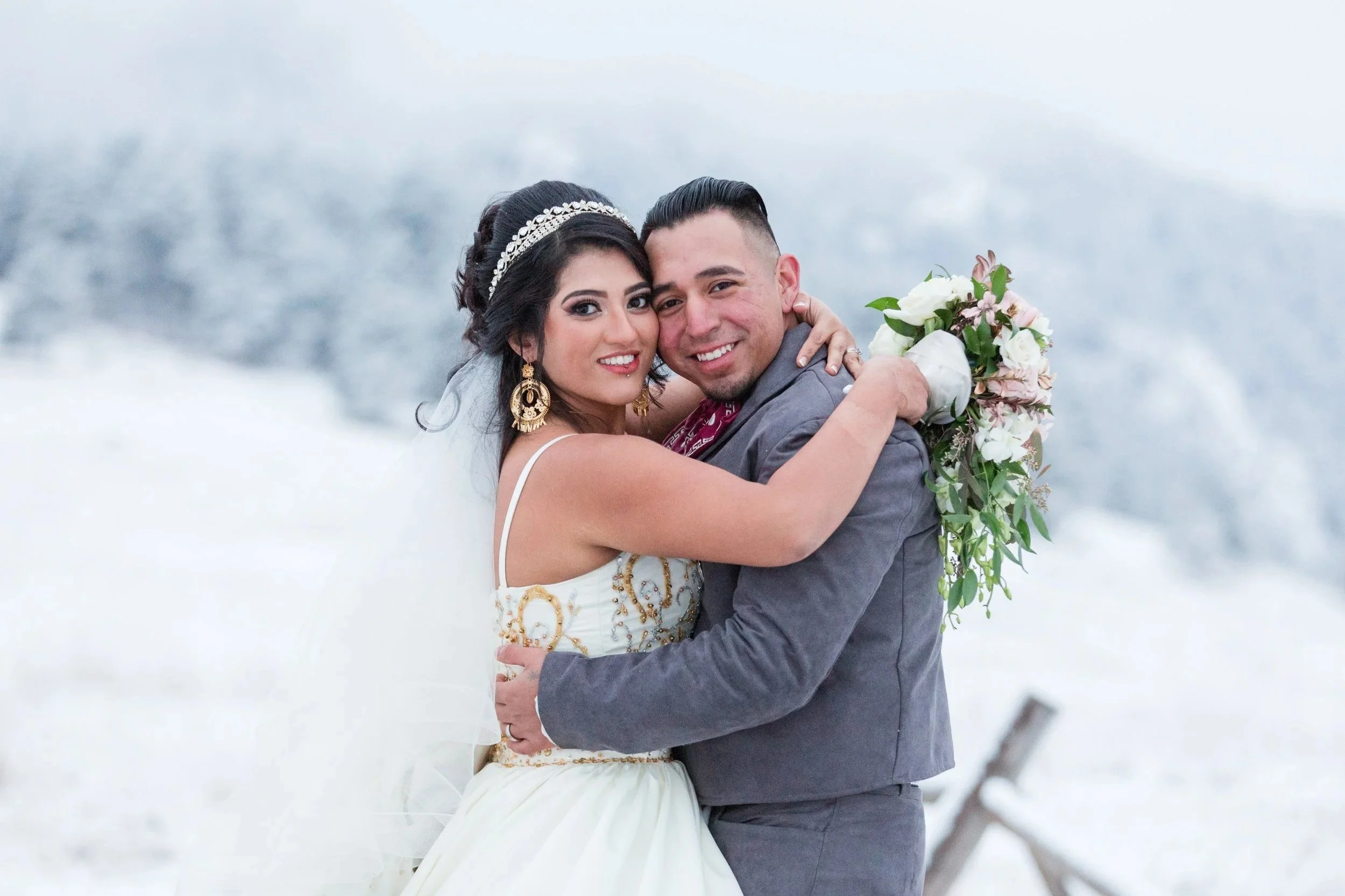 Winter bridal portrait at Chautauqua Park in Boulder, Colorado, showing a close-up of a bride holding her bouquet while embracing the groom in a snowy mountain setting.