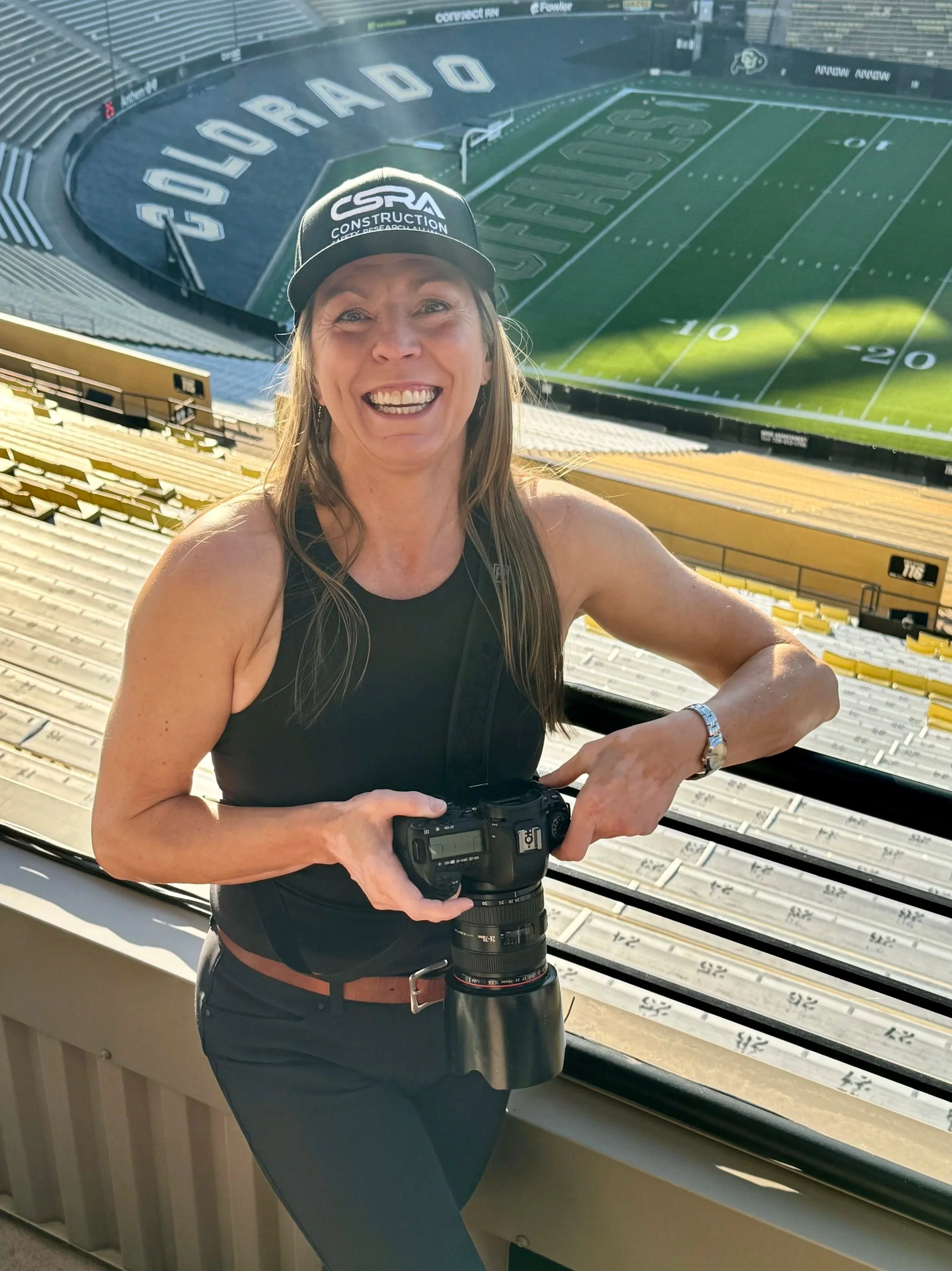 Professional photographer Lisa Doane smiling and holding a camera during the CSRA summit at Folsom Field, University of Colorado.