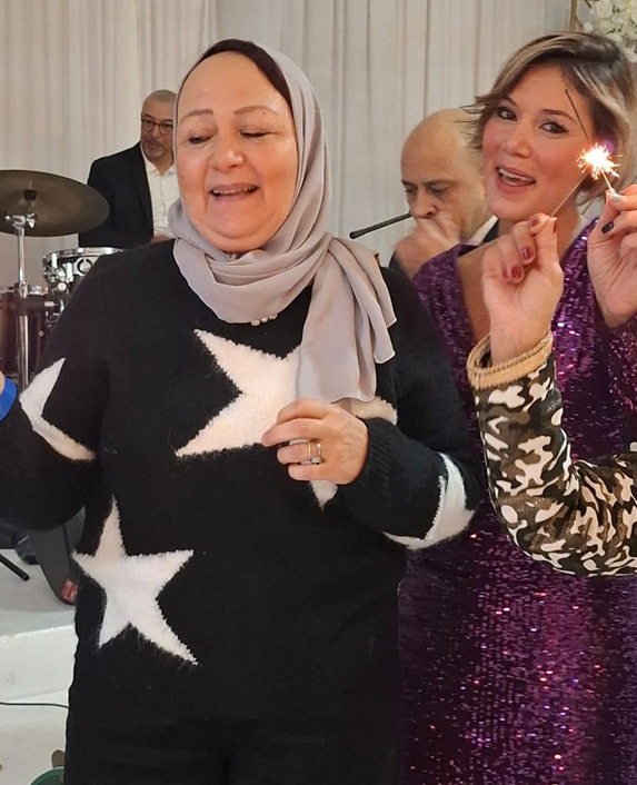 Women celebrating at a party with a sparker, background shows a band playing music.