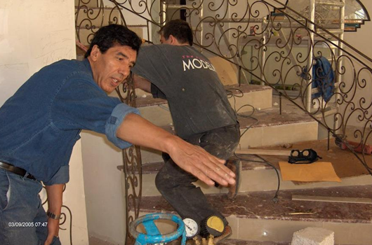 Two men working on a staircase, with tools and construction materials nearby.