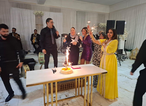People celebrating a birthday with a cake and sparklers in a decorated indoor setting.