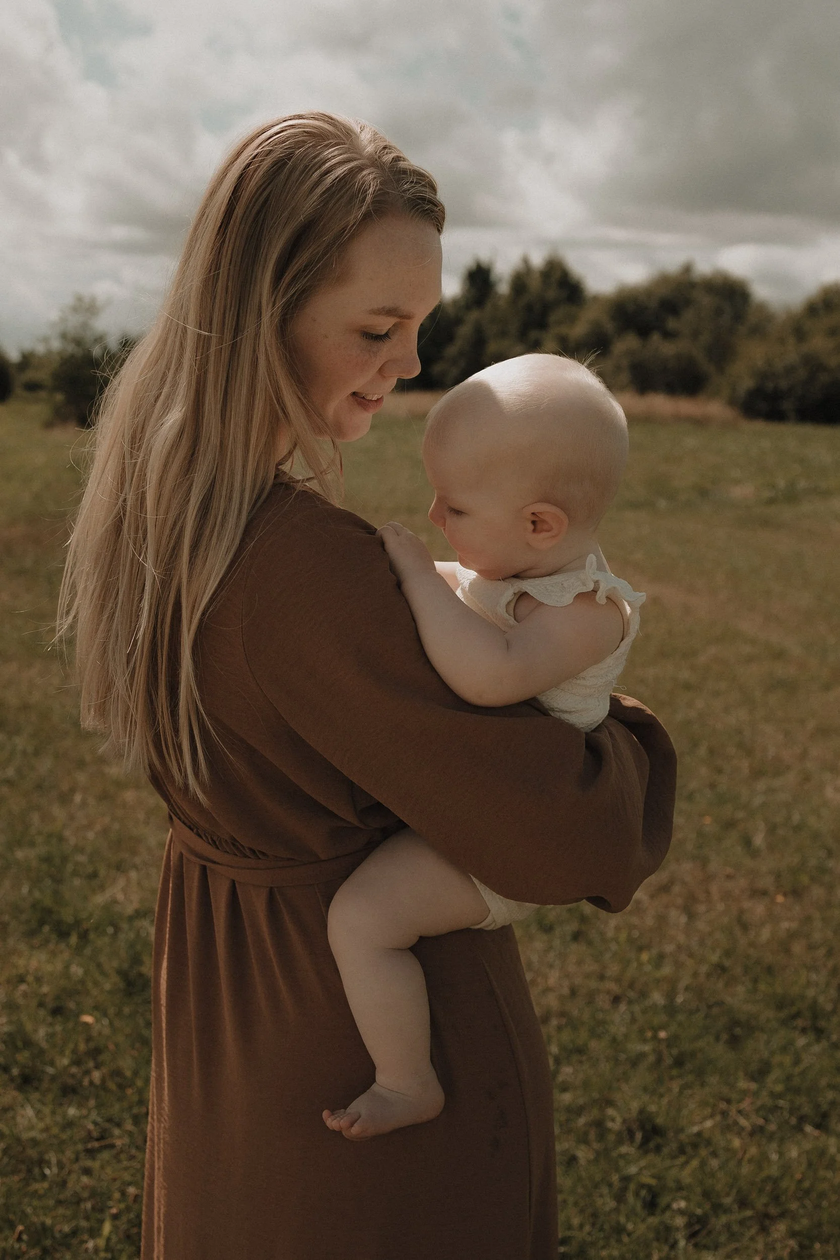 moeder knuffelt baby tijdens lifestyle motherhood fotografie in Emmen Drenthe