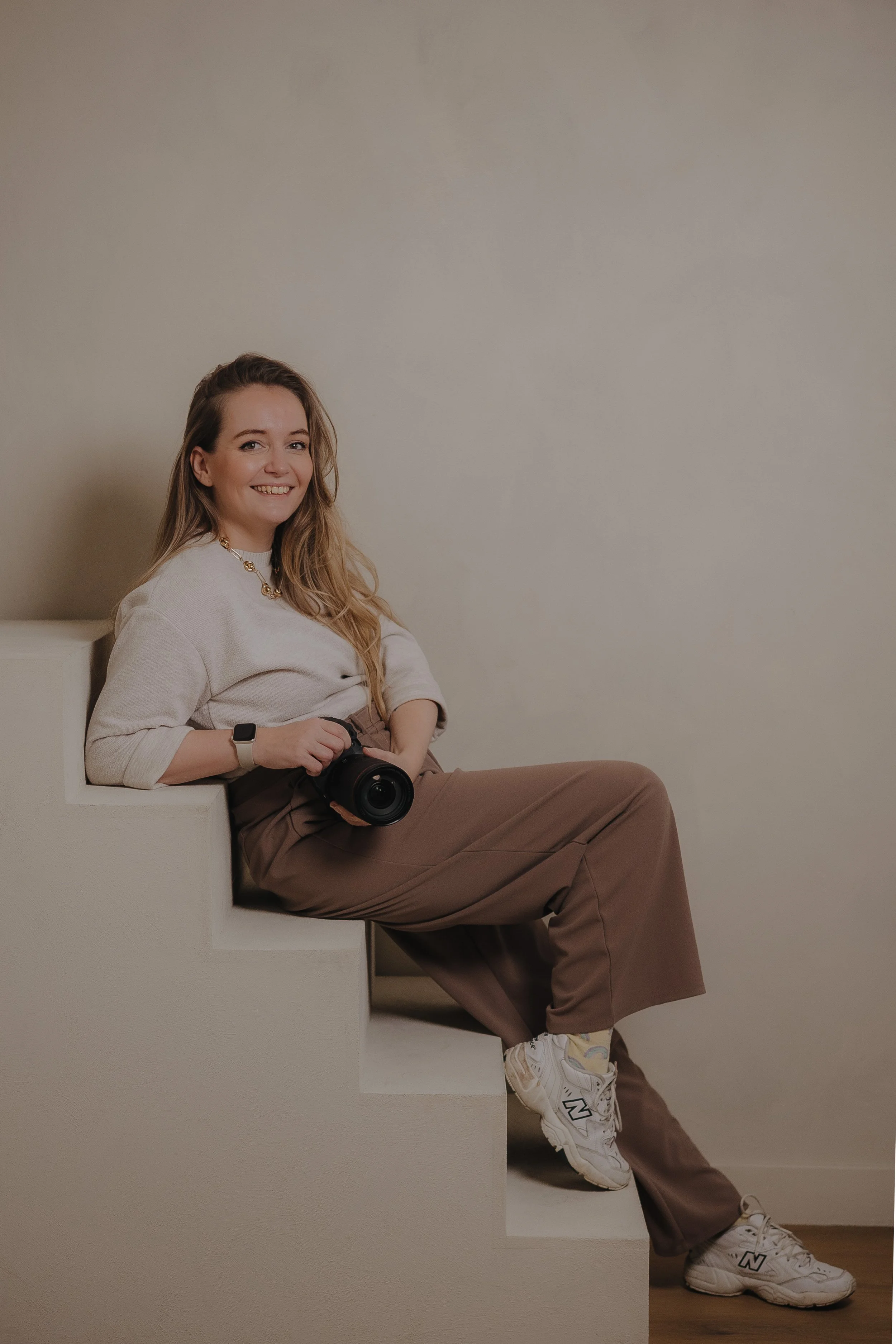 Fotograaf uit Drenthe op een stoel bij studio Laurant met canon camera in haar hand