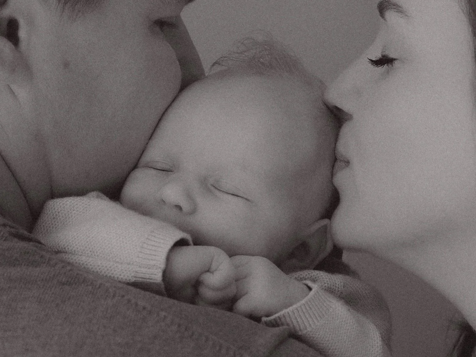 newborn shoot in Emmen Drenthe . Baby ligt bij papa en mama en krijgt een liefdevolle kus