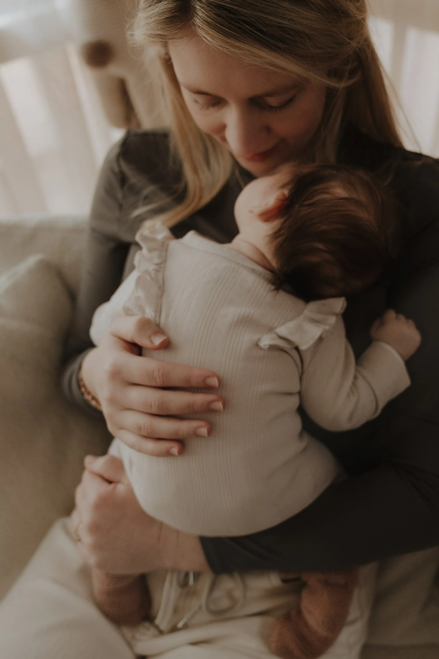 Newborn fotografie aan huis in Emmen – moeder houdt haar pasgeboren baby liefdevol vast
