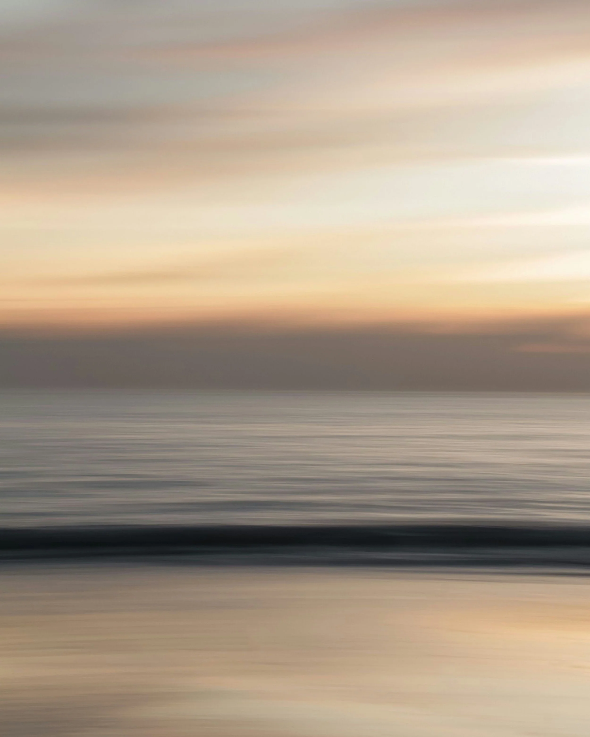 Blurred abstract image of a sunset over the ocean with colors blending from light pink to darker shades.