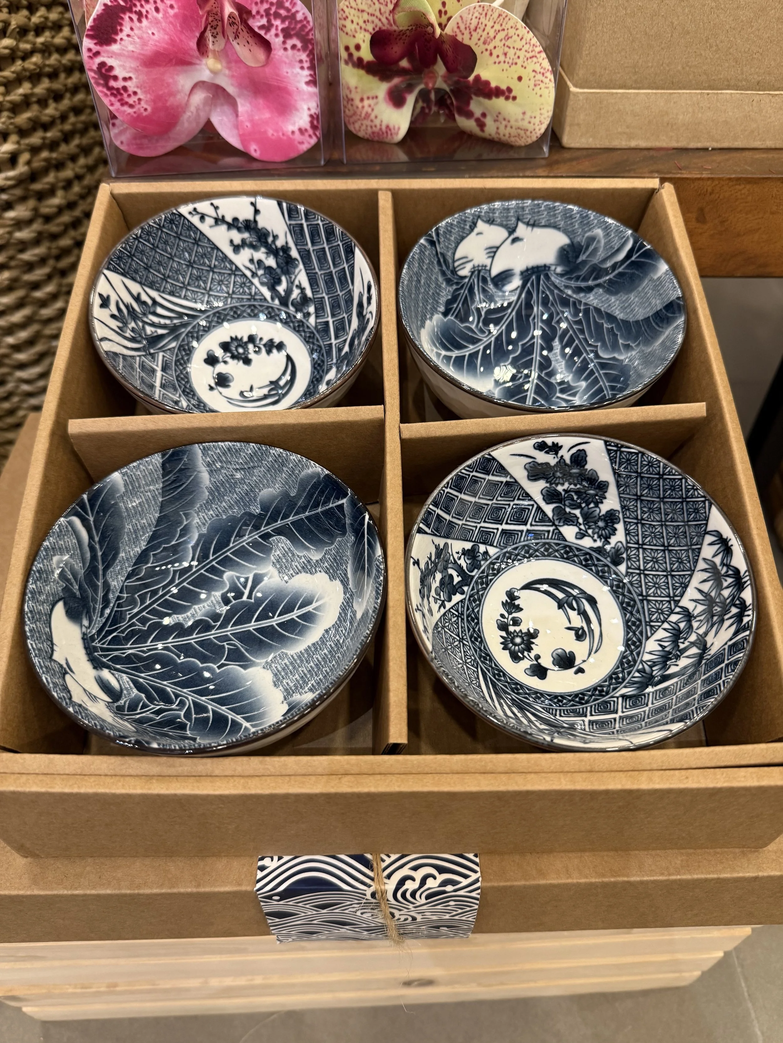 Set of four blue and white patterned ceramic bowls inside a wooden display box.