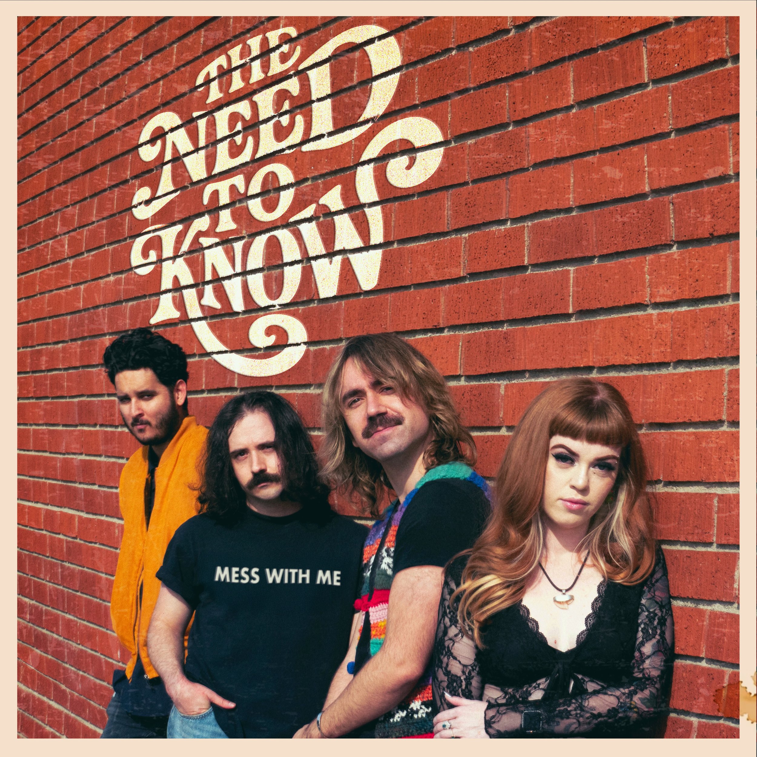 Four members of the rock band The Need To Know lean confidently against a brick wall. The band's name is painted on the wall above them. The single's title is on the shirt of the drummer.