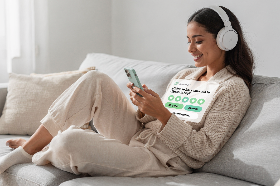 Muestra a una mujer sentada en un sofá viendo su teléfono móvil con auriculares, con un cuadro de evaluación de salud digestiva en su lado.
