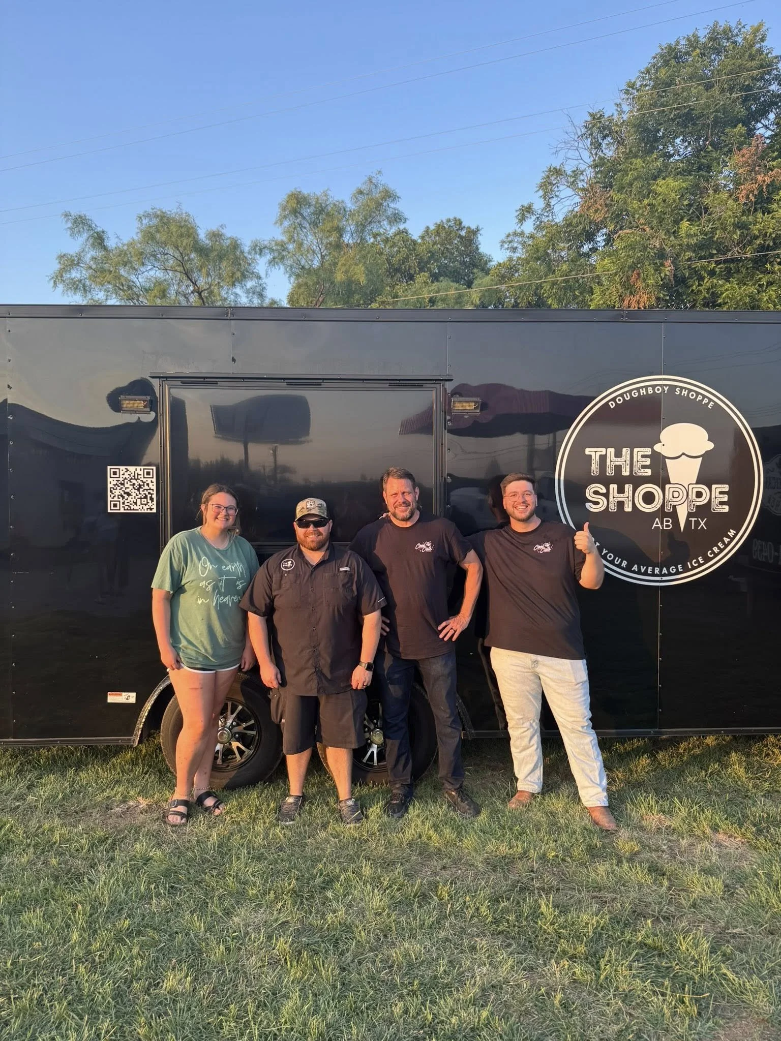 Four people standing in front of a black food truck labeled "The Shoppe" with the words "Doughboy Shoppe" and "AB TX"; one person giving a thumbs up.