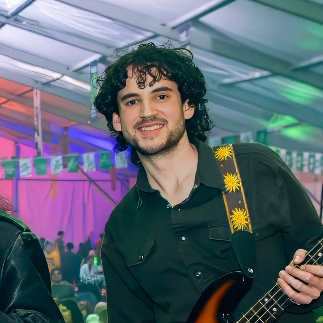 Cole Derry of Sean Daly and The Shams smiling on stage with his bass at a packed Portland St. Patrick's Day show.