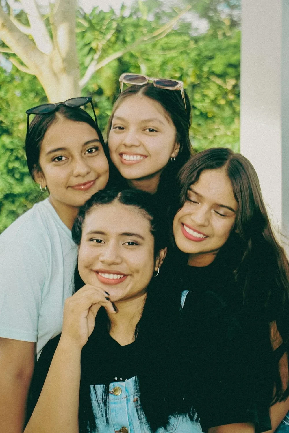 Four diverse teenage girls smiling together in warm outdoor setting