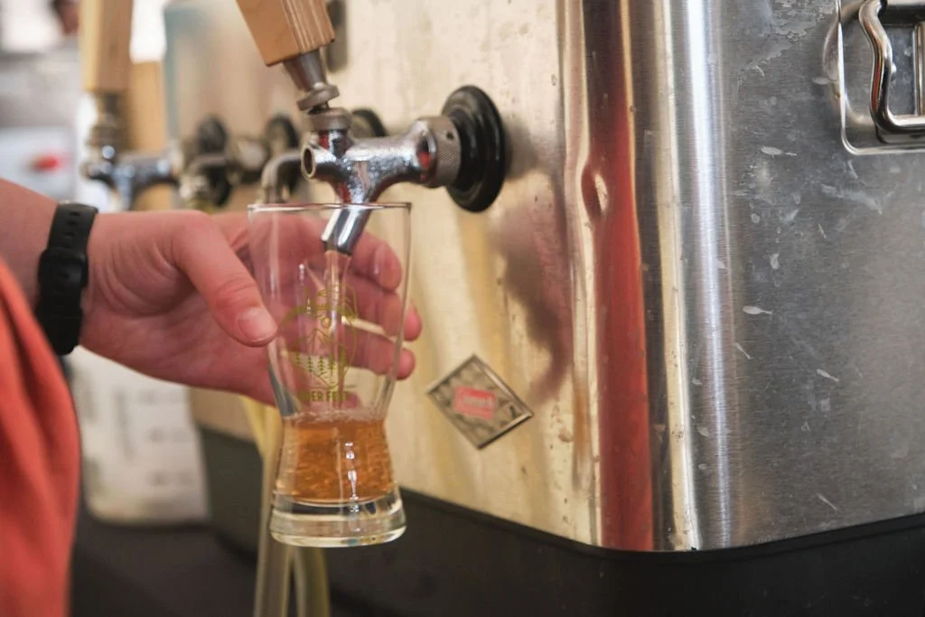 Person pouring beer from a tap into a glass."}