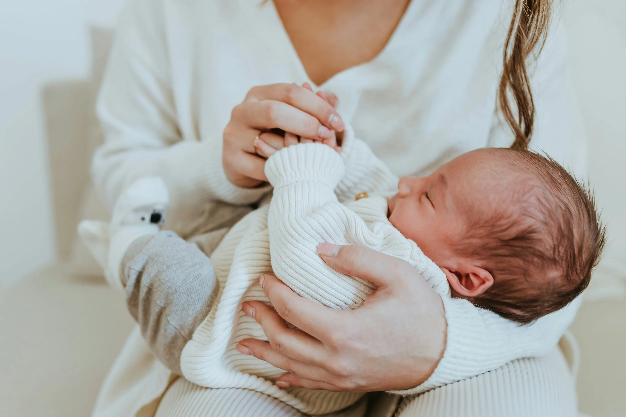 A woman holding a sleeping baby in her arms, with the baby's face resting against her chest.