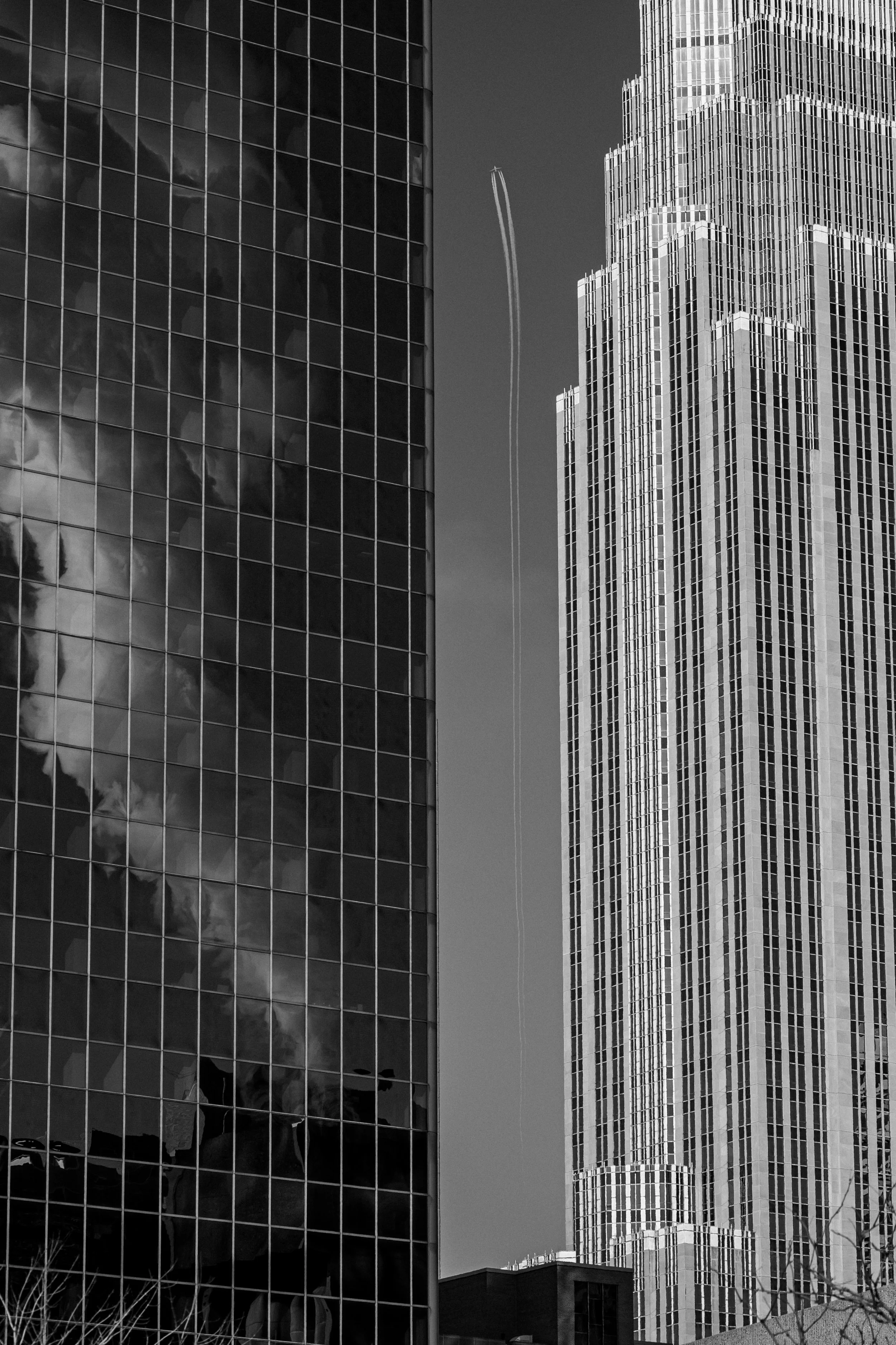 The contrail of a plane streaks between skyscrapers in downtown Minneapolis.