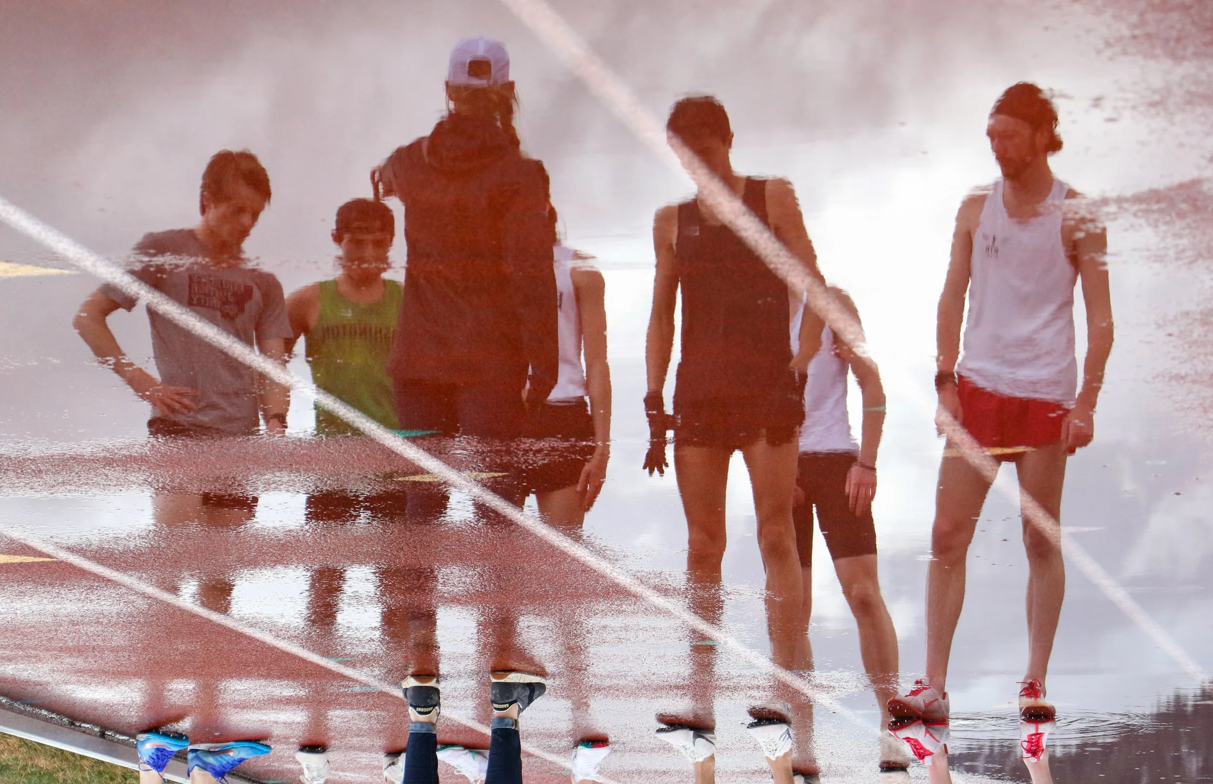 University of Montana steeplechase runners are reflected in a puddle on the track as they begin a workout at Dornblaser Field in Missoula, Mont.