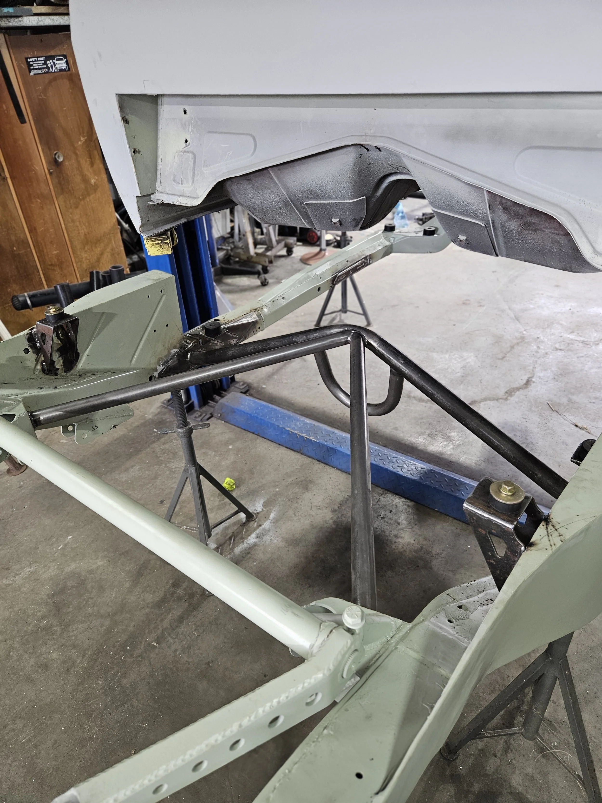 Car frame on jack stands with the undercarriage exposed in a garage workshop.