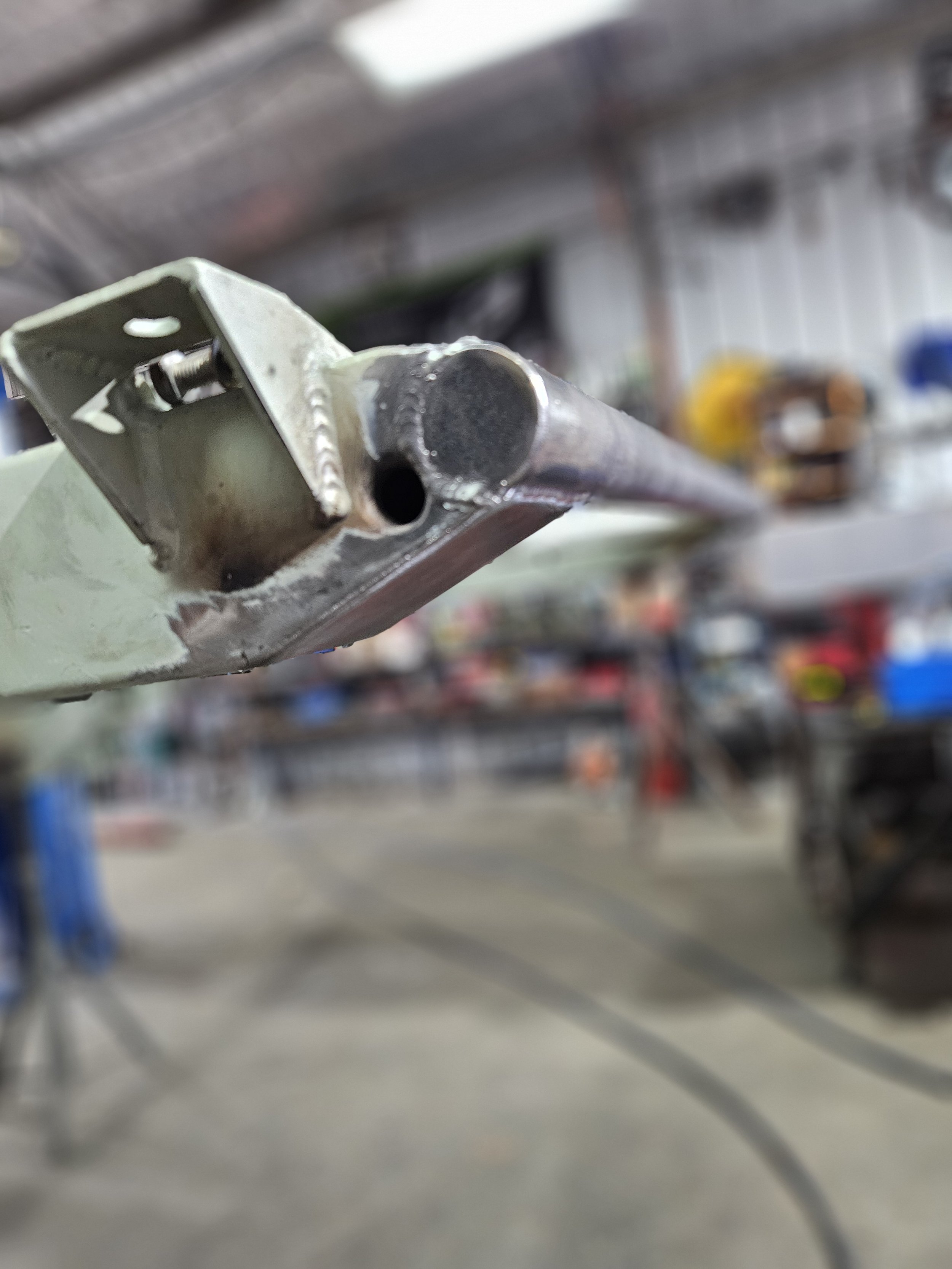 Close-up of a metal tube or pipe mounted on a metal frame in a workshop setting.