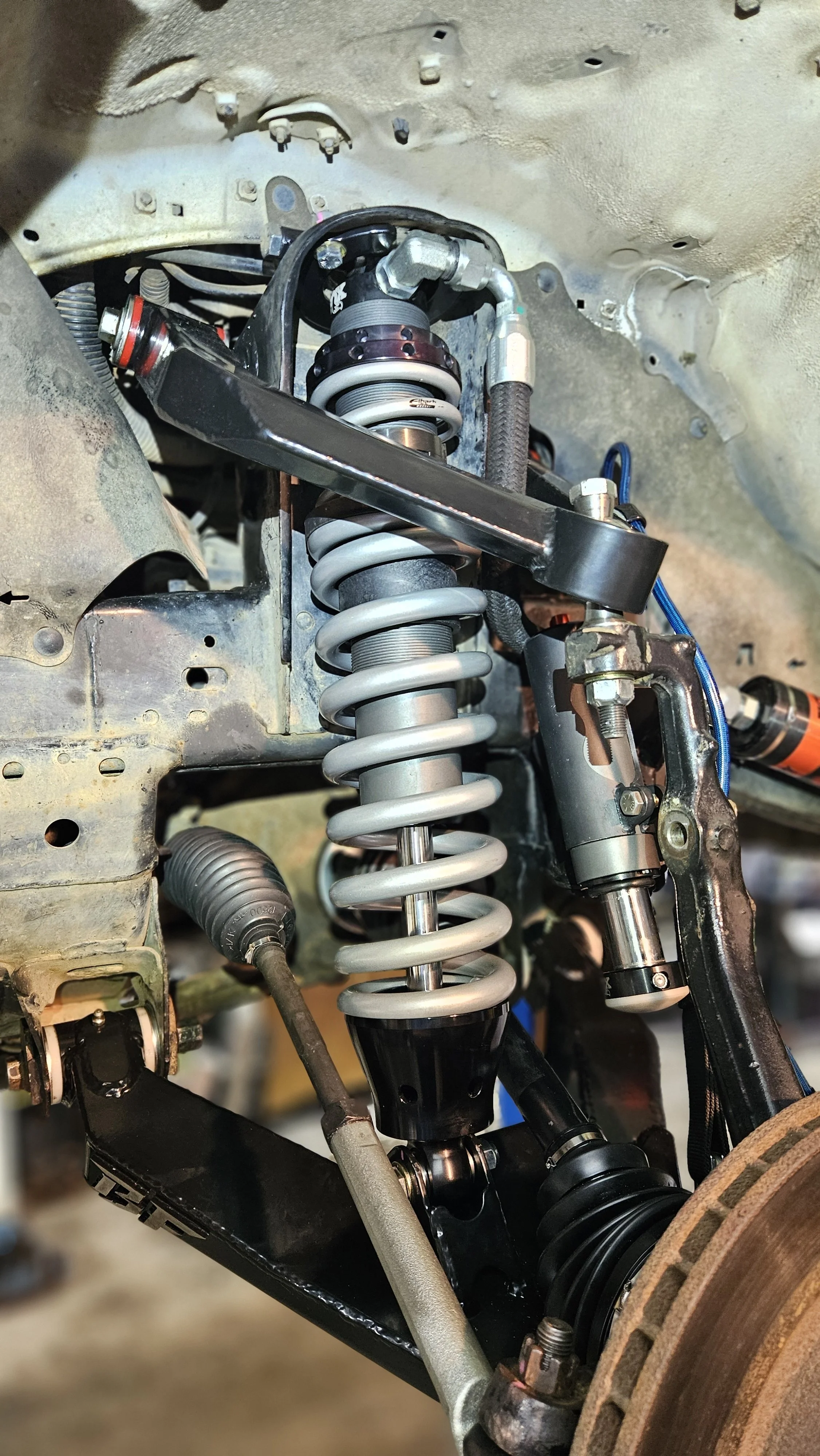 Close-up of a vehicle suspension system with coil spring, shock absorber, and related components.