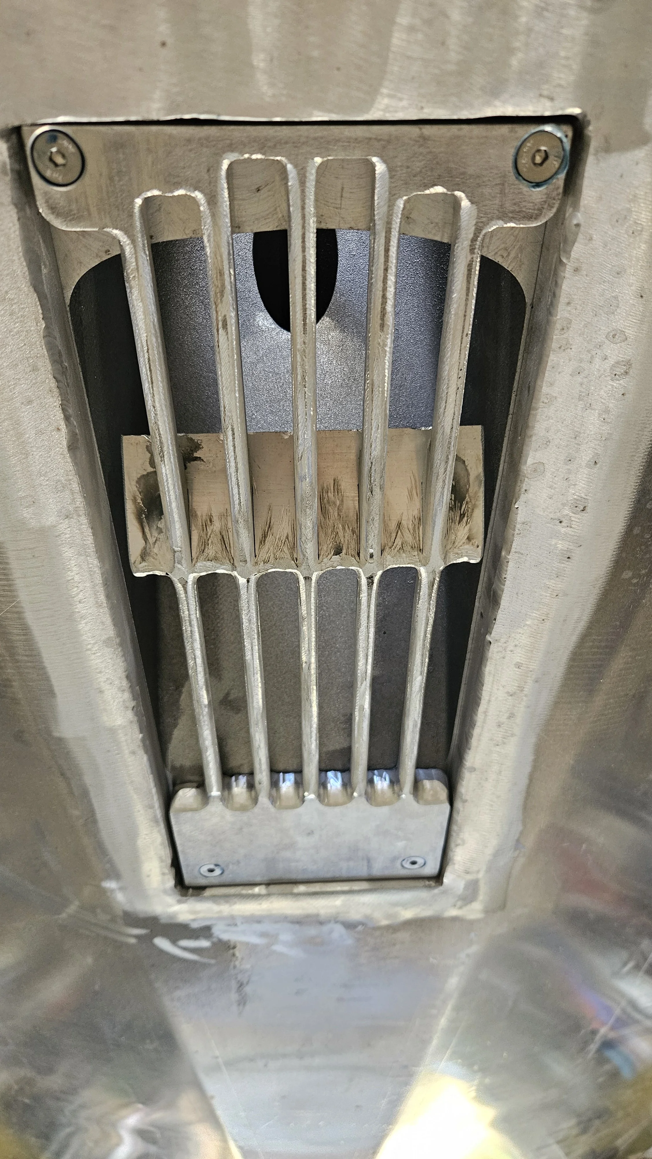 A metal grate covering a drainage or ventilation opening in a ceiling or floor.