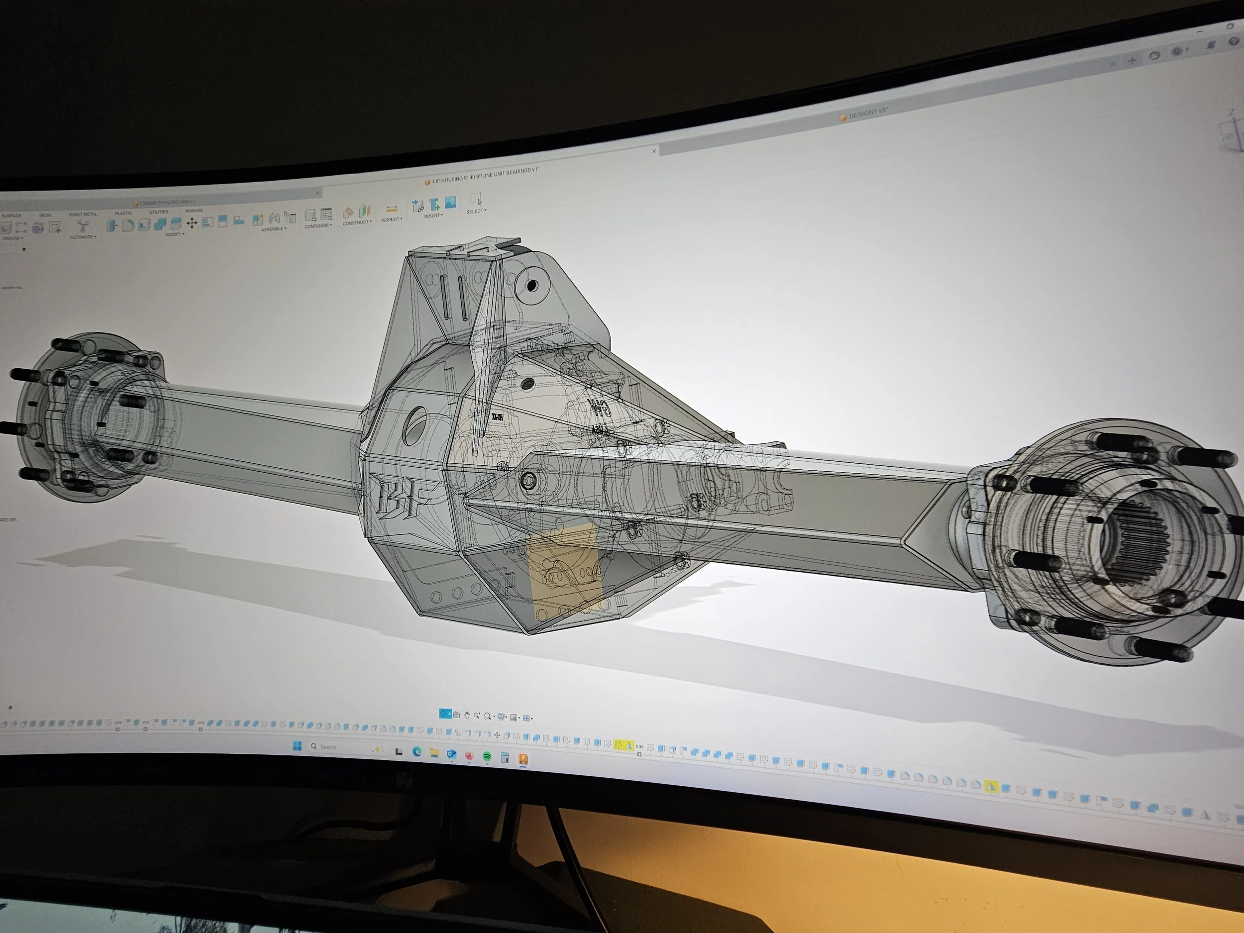 Computer-aided design (CAD) model of a mechanical component with a long cylindrical shape and detailed inner and outer structures displayed on a monitor.
