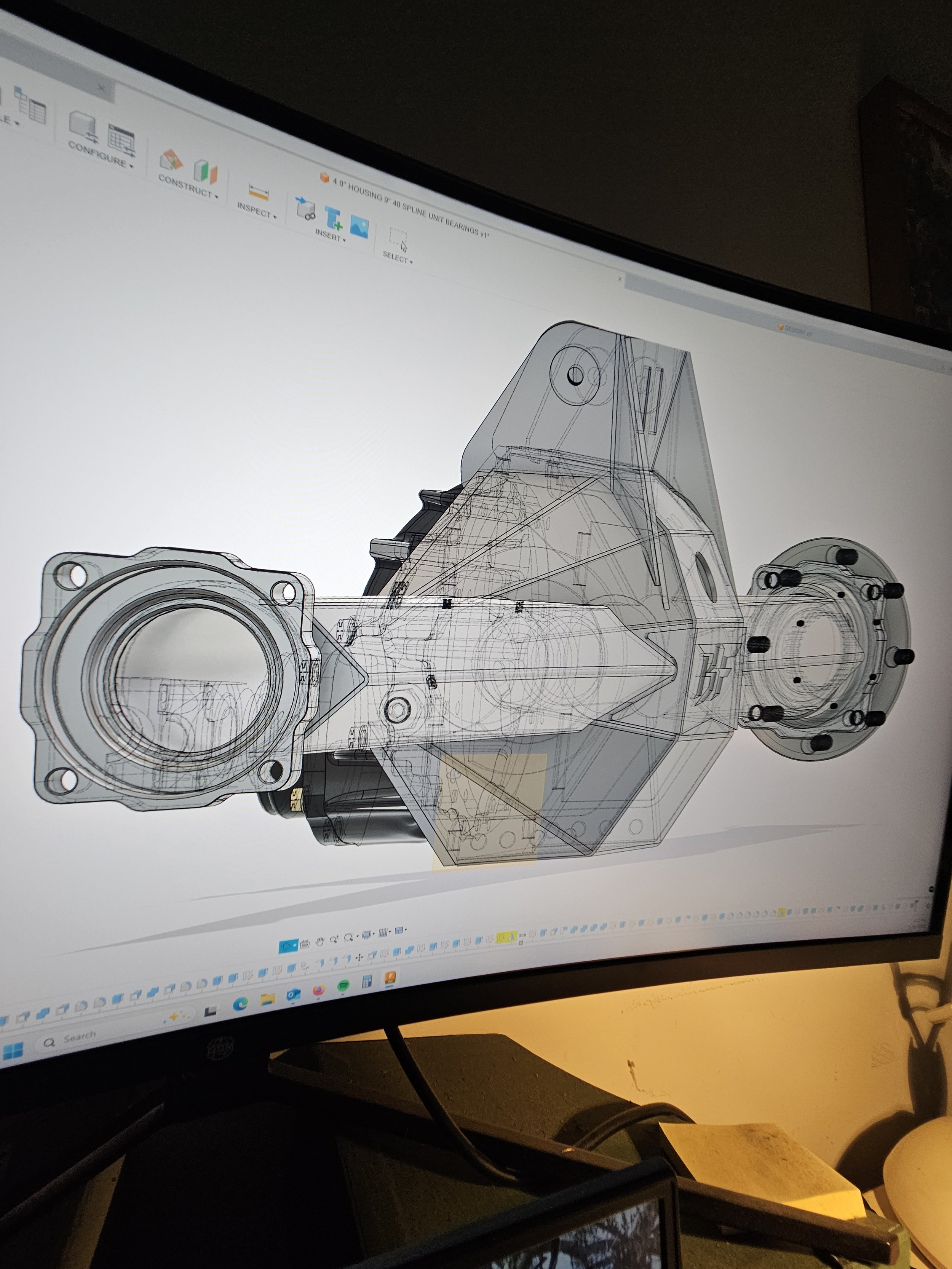 Computer monitor displaying a technical CAD drawing of a mechanical component with transparent overlays showing detailed design and structure.
