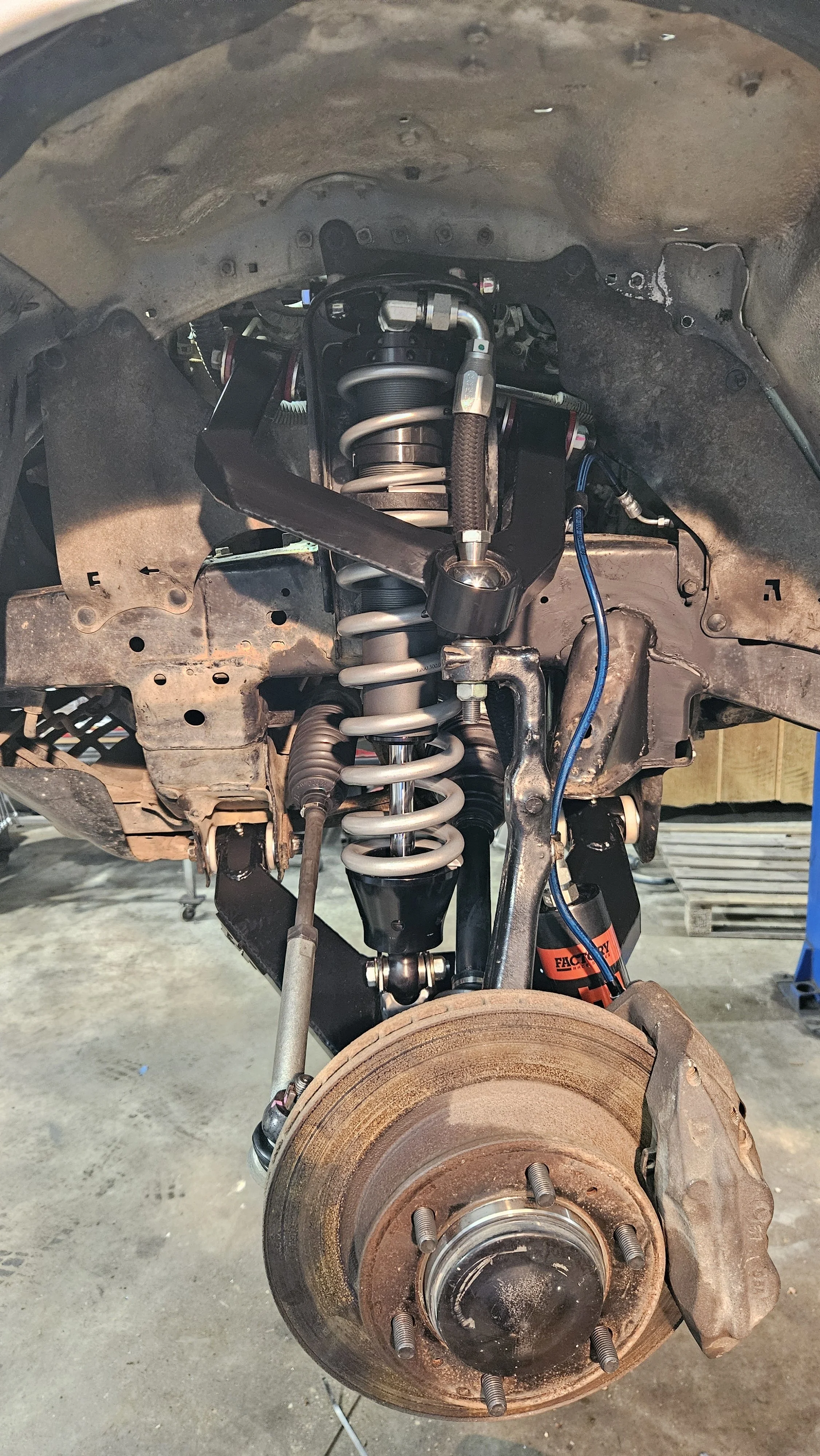 View of a car's suspension system showing an installed coil spring, shock absorber, and brake assembly with the wheel removed.