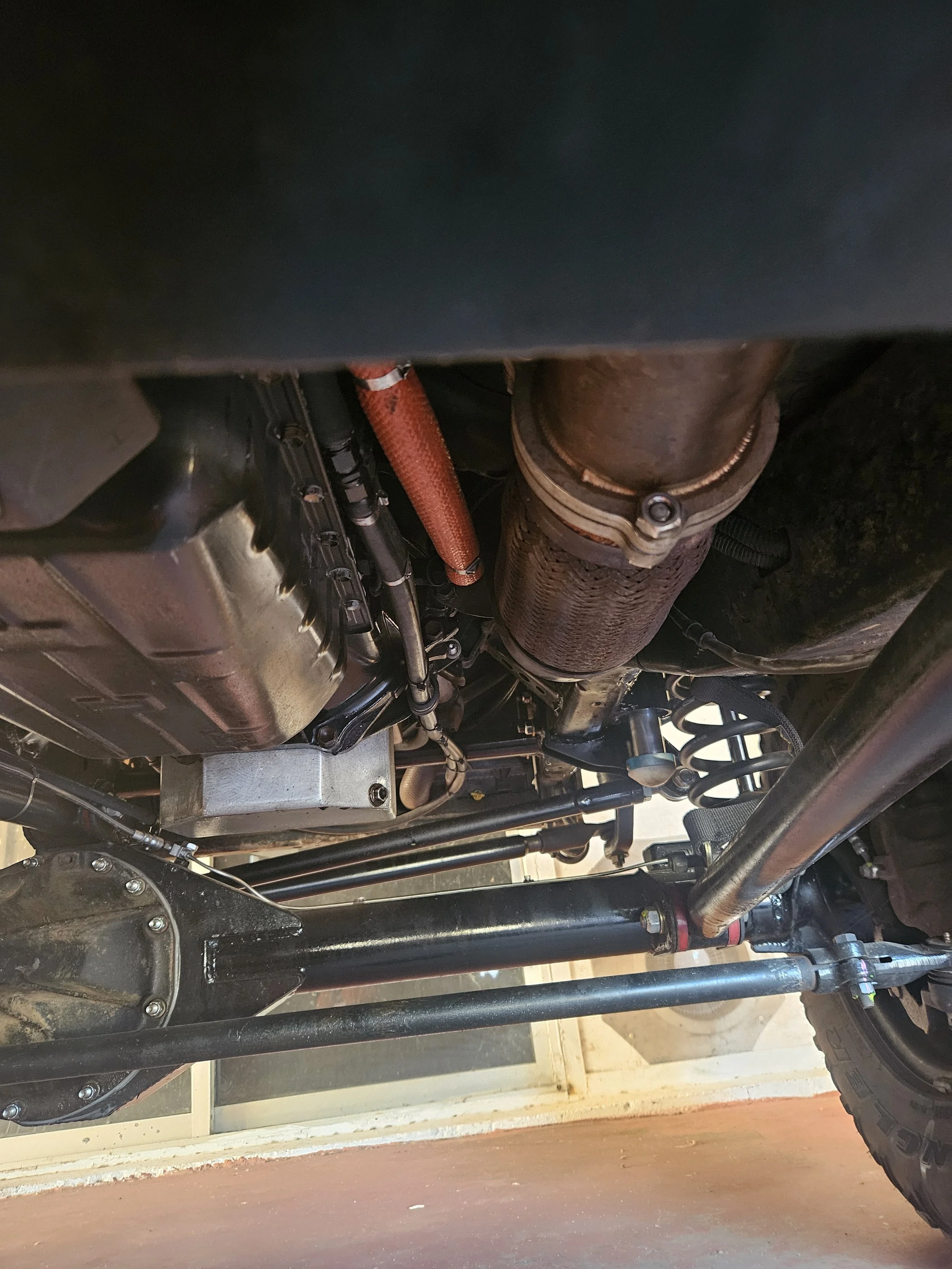 Underneath view of a vehicle showing the drivetrain, exhaust system, suspension components, and part of the frame.