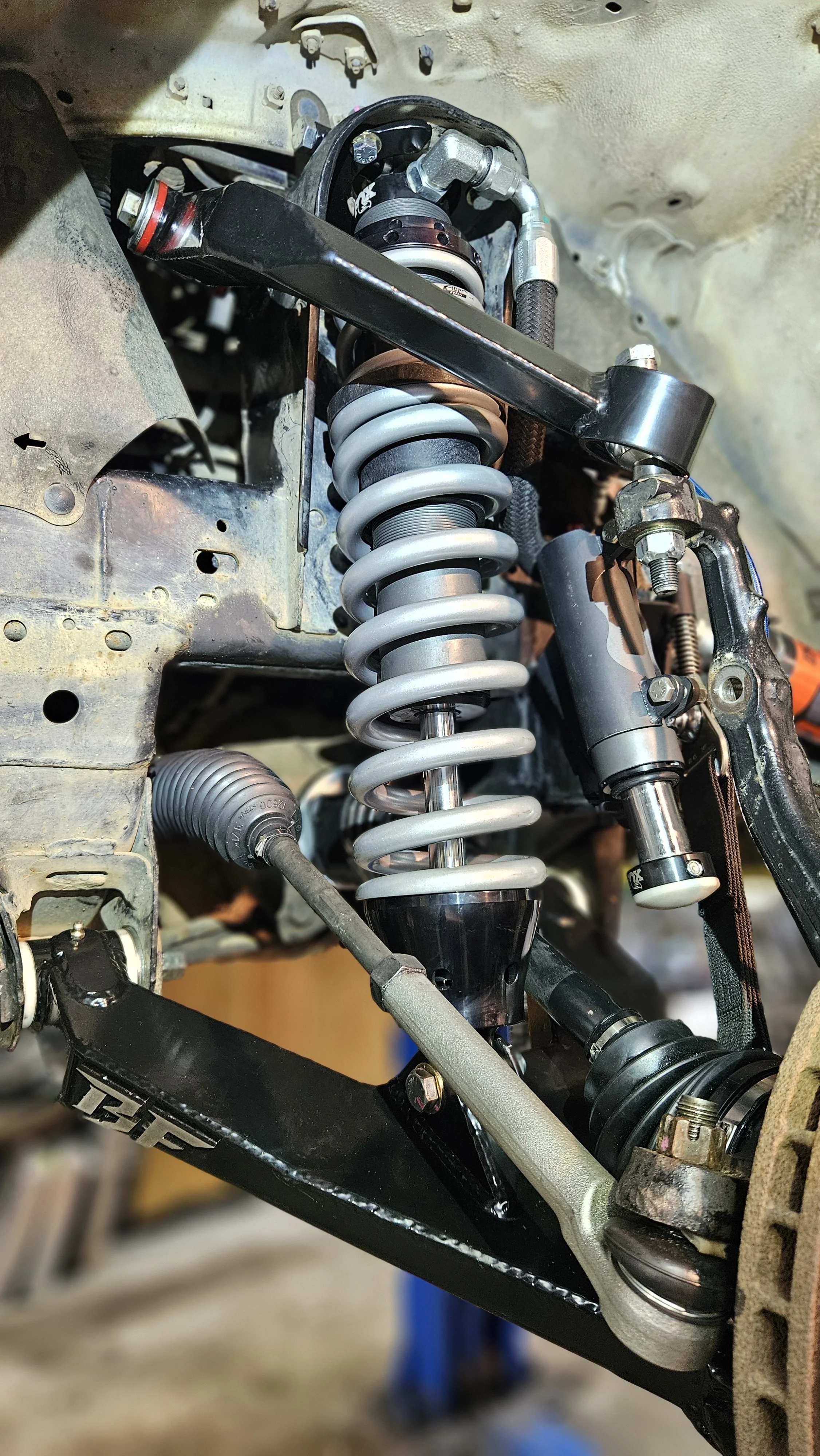 Close-up of a car's suspension system, showing a coil spring, shock absorber, and various suspension components.