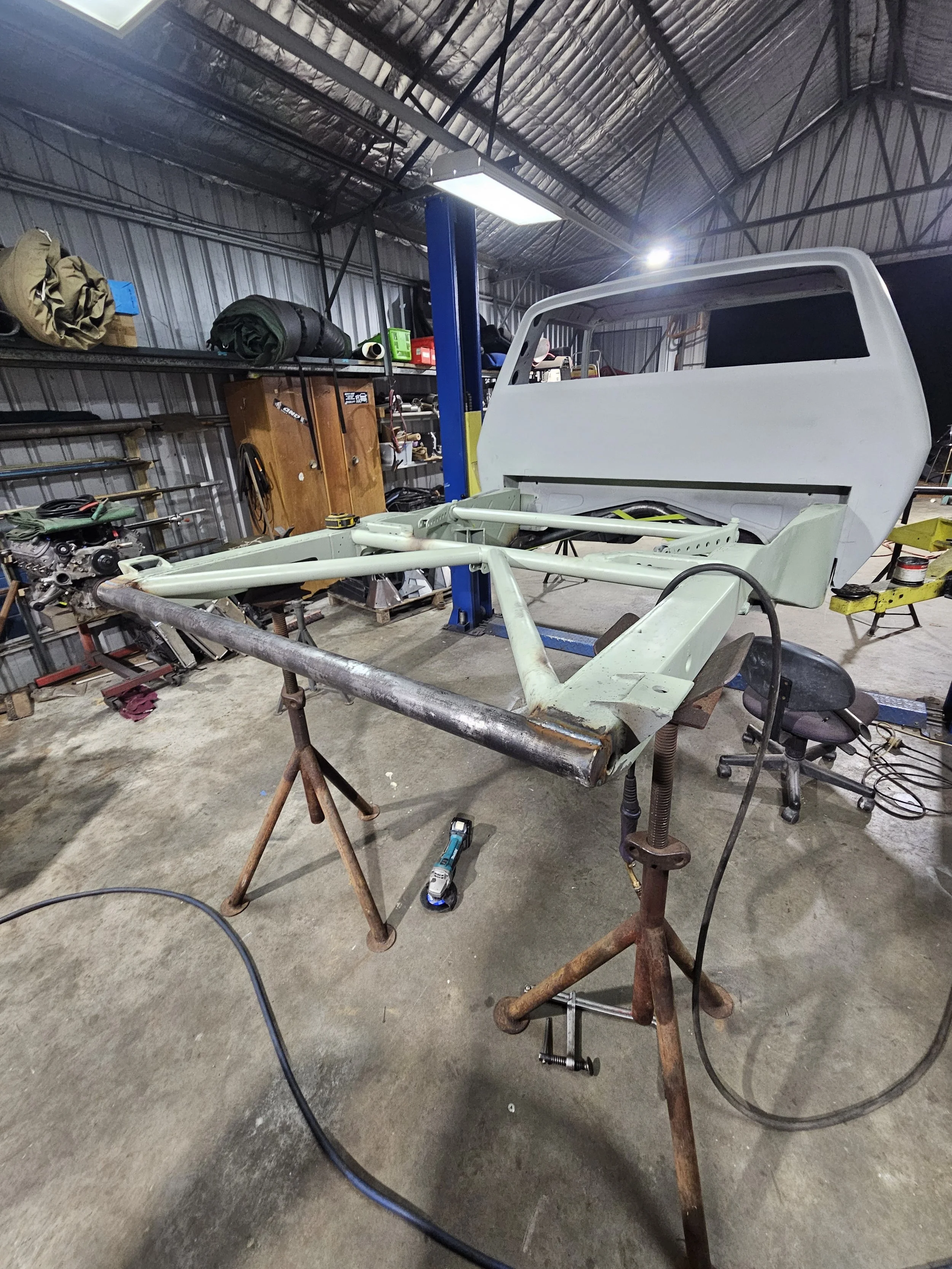 A partly assembled painted vehicle cab frame on workshop tables with tools and equipment around in a garage or workshop.