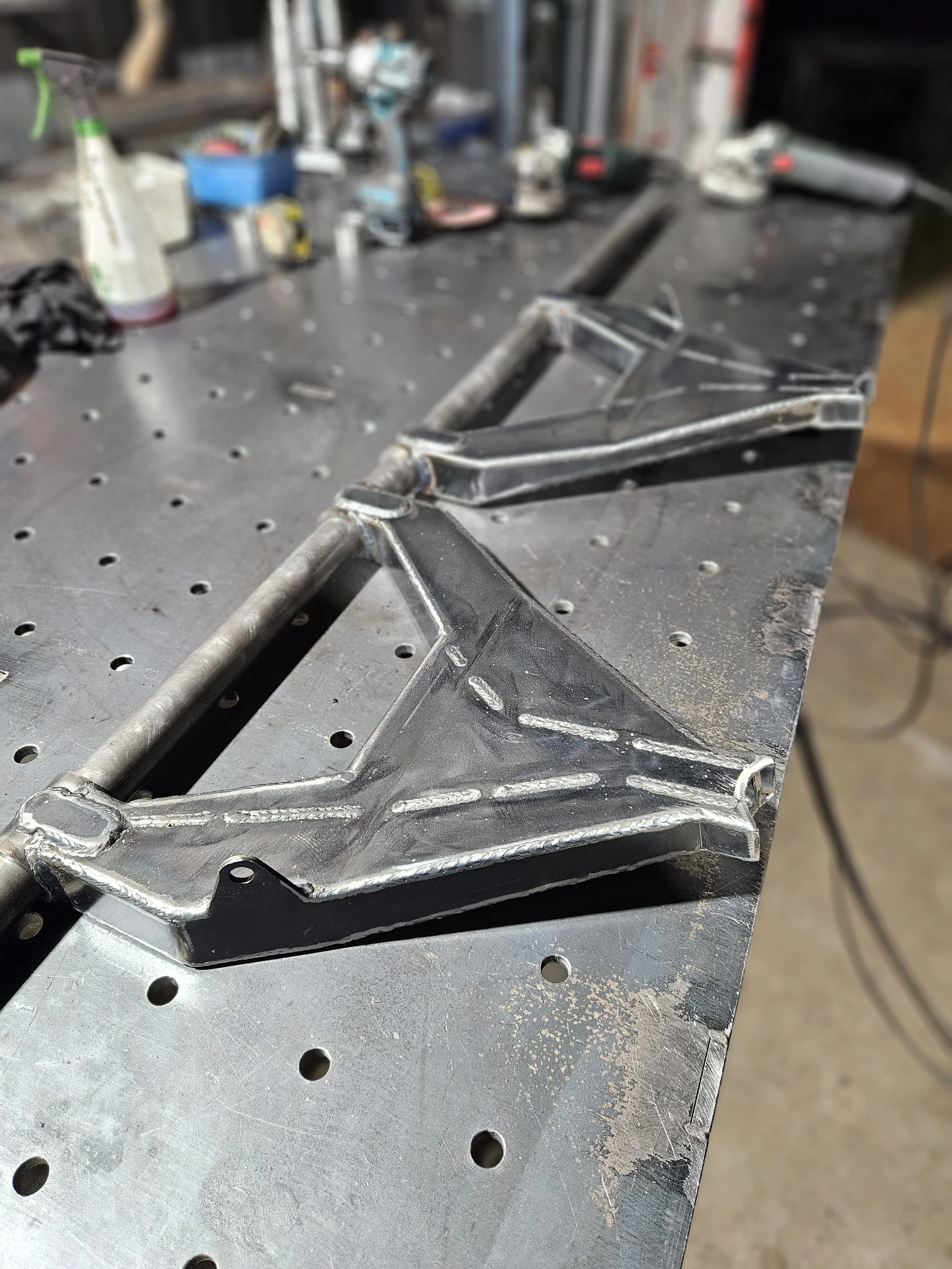 Metalwork project with welded triangular frames on a workbench in a workshop.