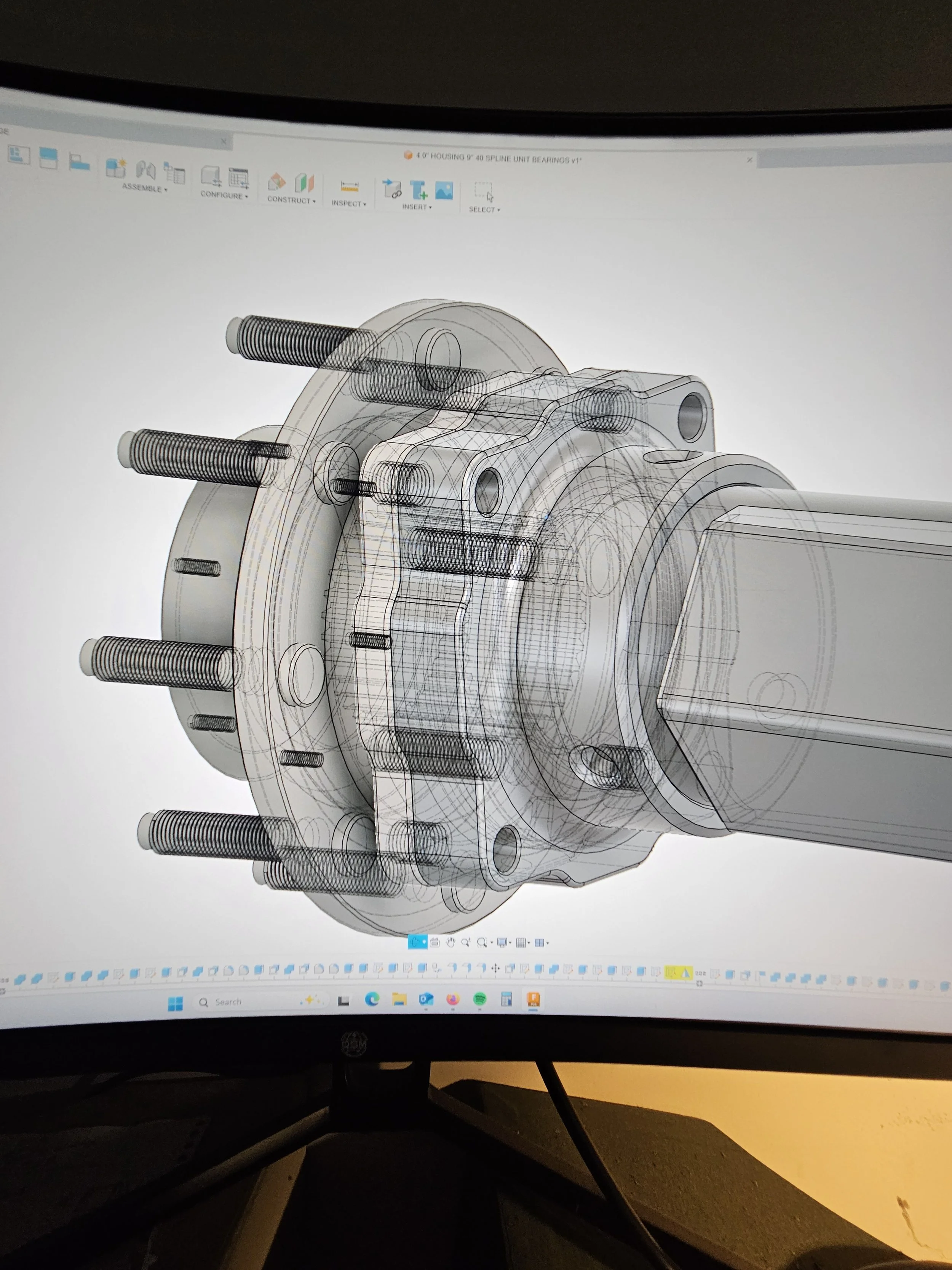 A computer screen displaying a 3D CAD model of a mechanical component, possibly a hub or bearing assembly with multiple bolts and detailed features.