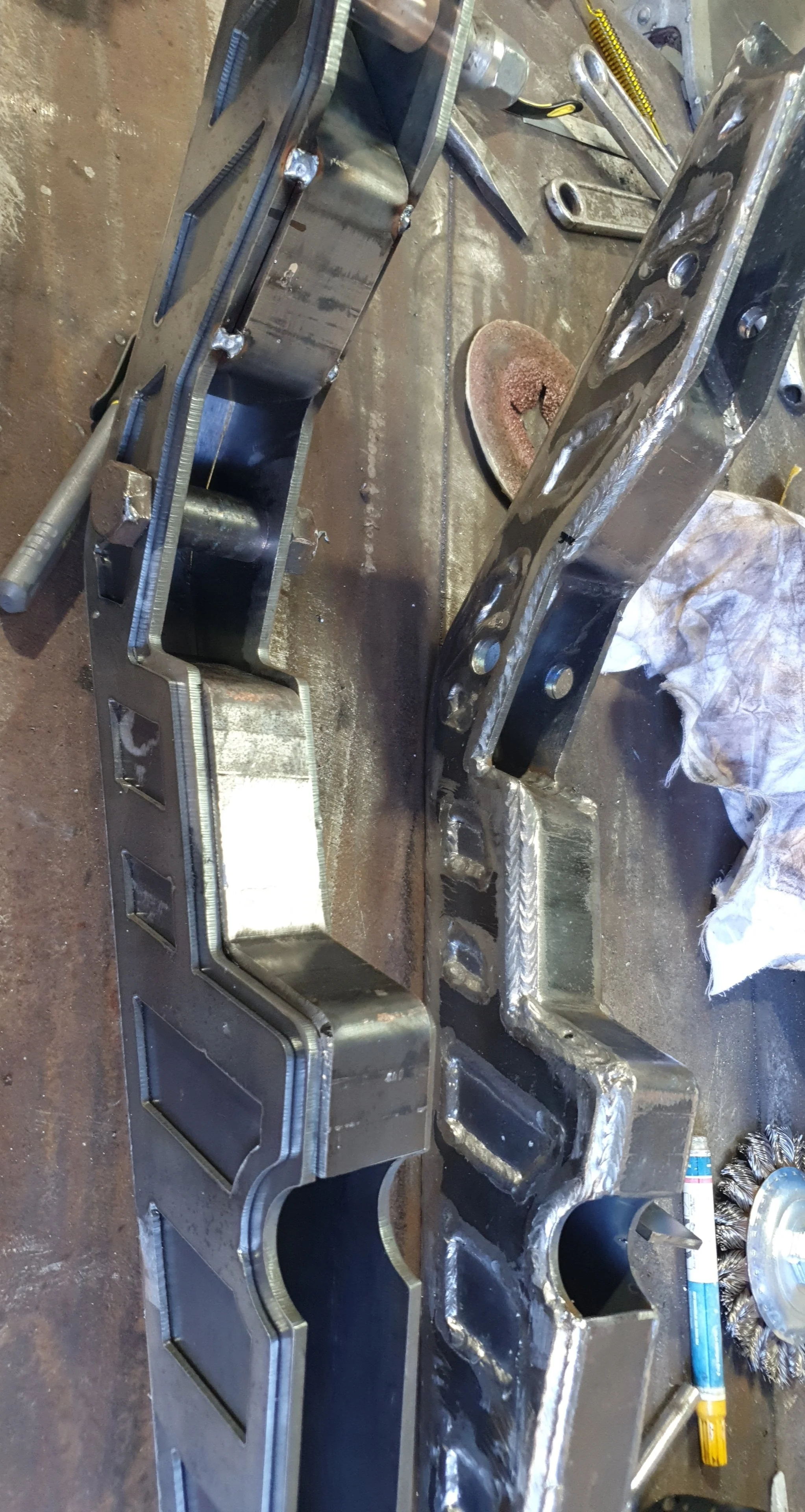 Metal fabrication workshop with welded metal frames, tools, and equipment on a work surface.