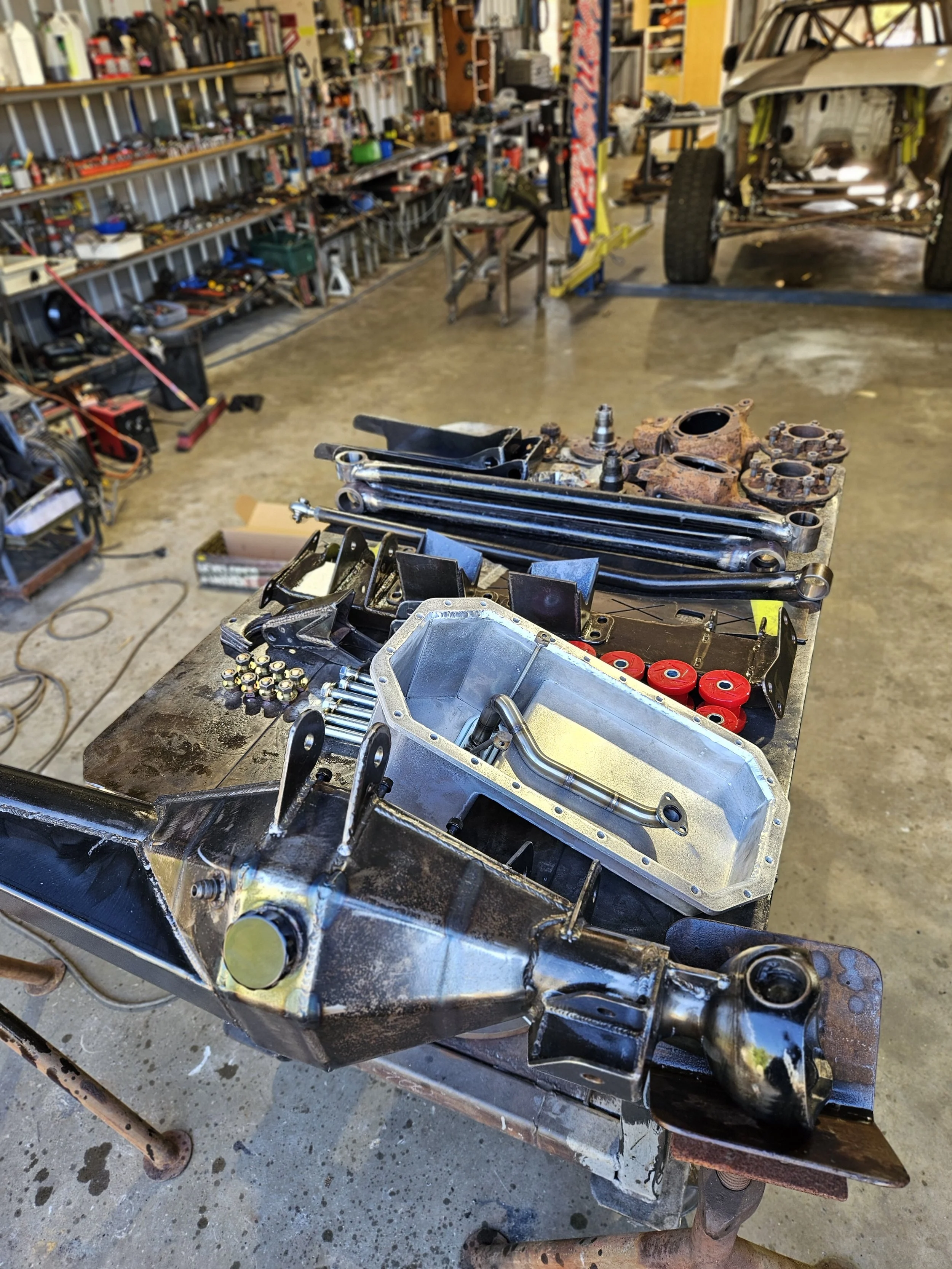 Workbenches with car engine parts, tools, and mechanical components in an auto repair workshop.