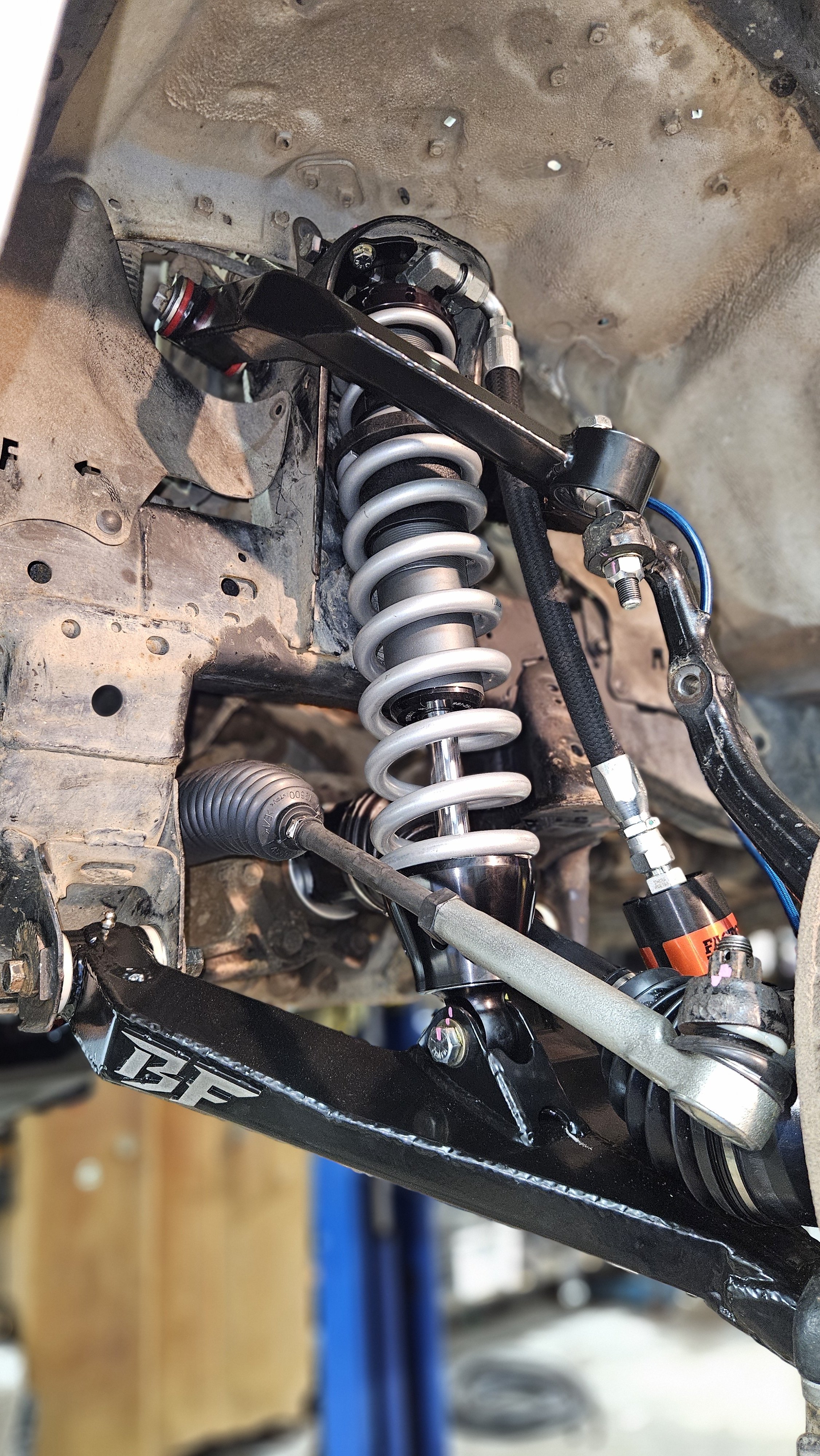 Close-up of a vehicle's suspension system, showing a coil spring, shock absorber, and control arm.