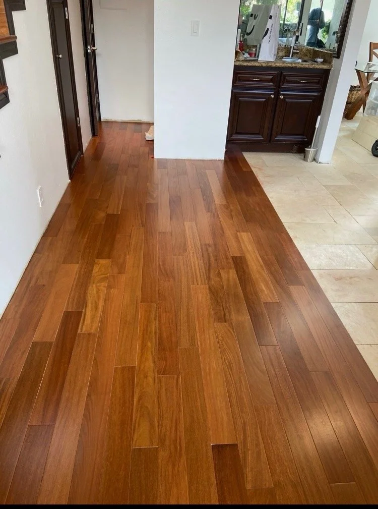Wooden flooring in a kitchen area with a transition to tile flooring.