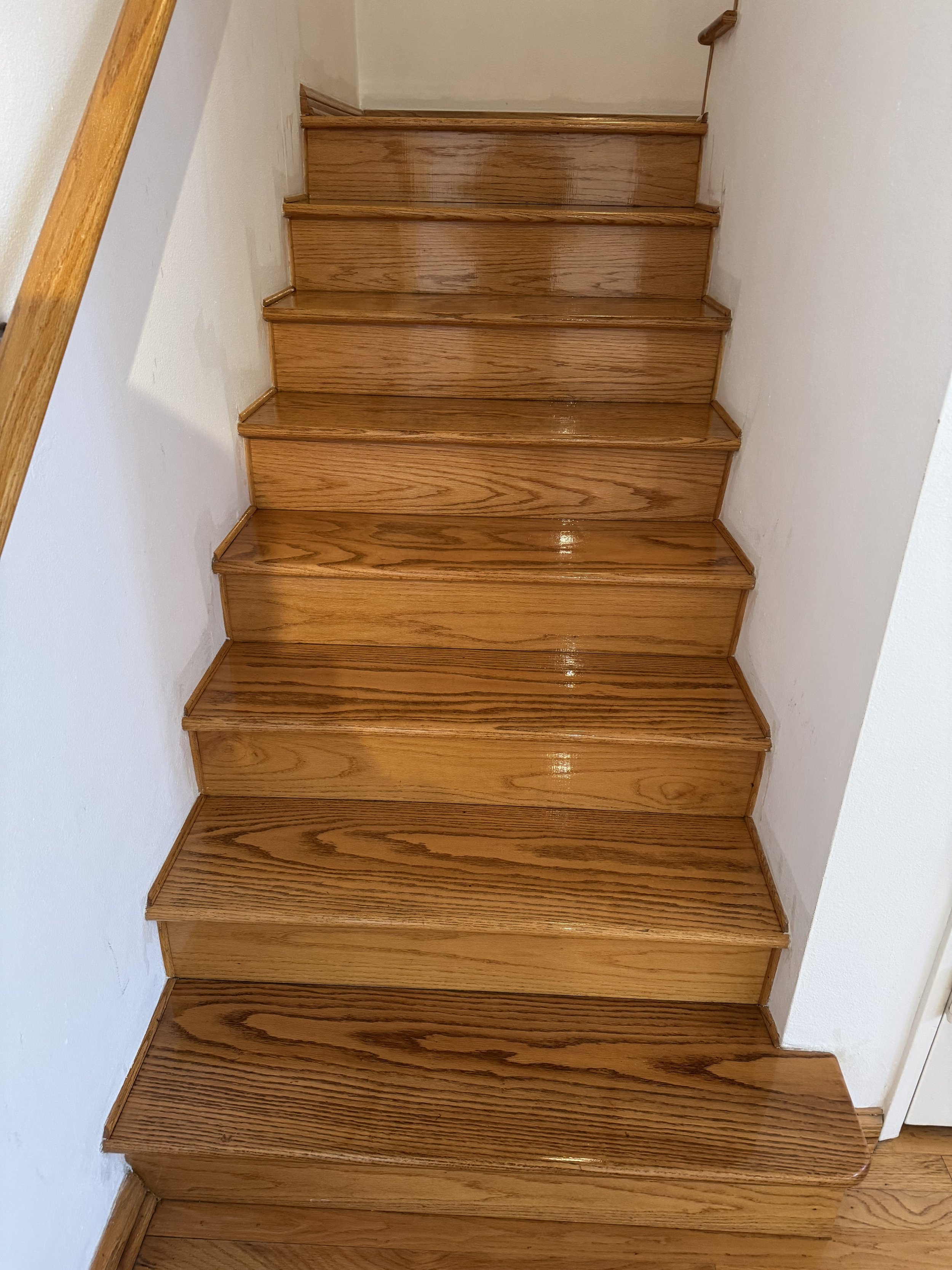 Wooden staircase with ten steps and a brown handrail on the side.