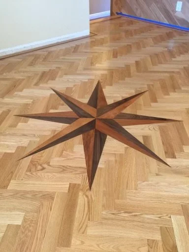 A wooden star-shaped inlay design on a hardwood floor in a room.