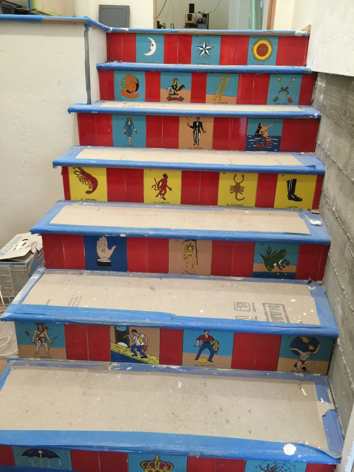 Painted staircase with steps decorated with colorful murals of various traditional Mexican symbols, figures, and designs, including a snake, scorpion, scuba diver, and cultural figures.