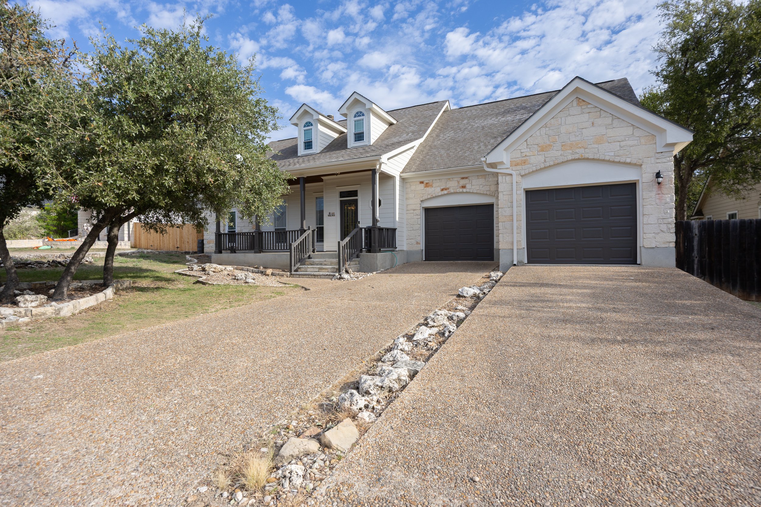 This Hill Country native limestone 2-story home has a fresh, recently painted exterior, a spacious covered front porch, and an attached two-car garage