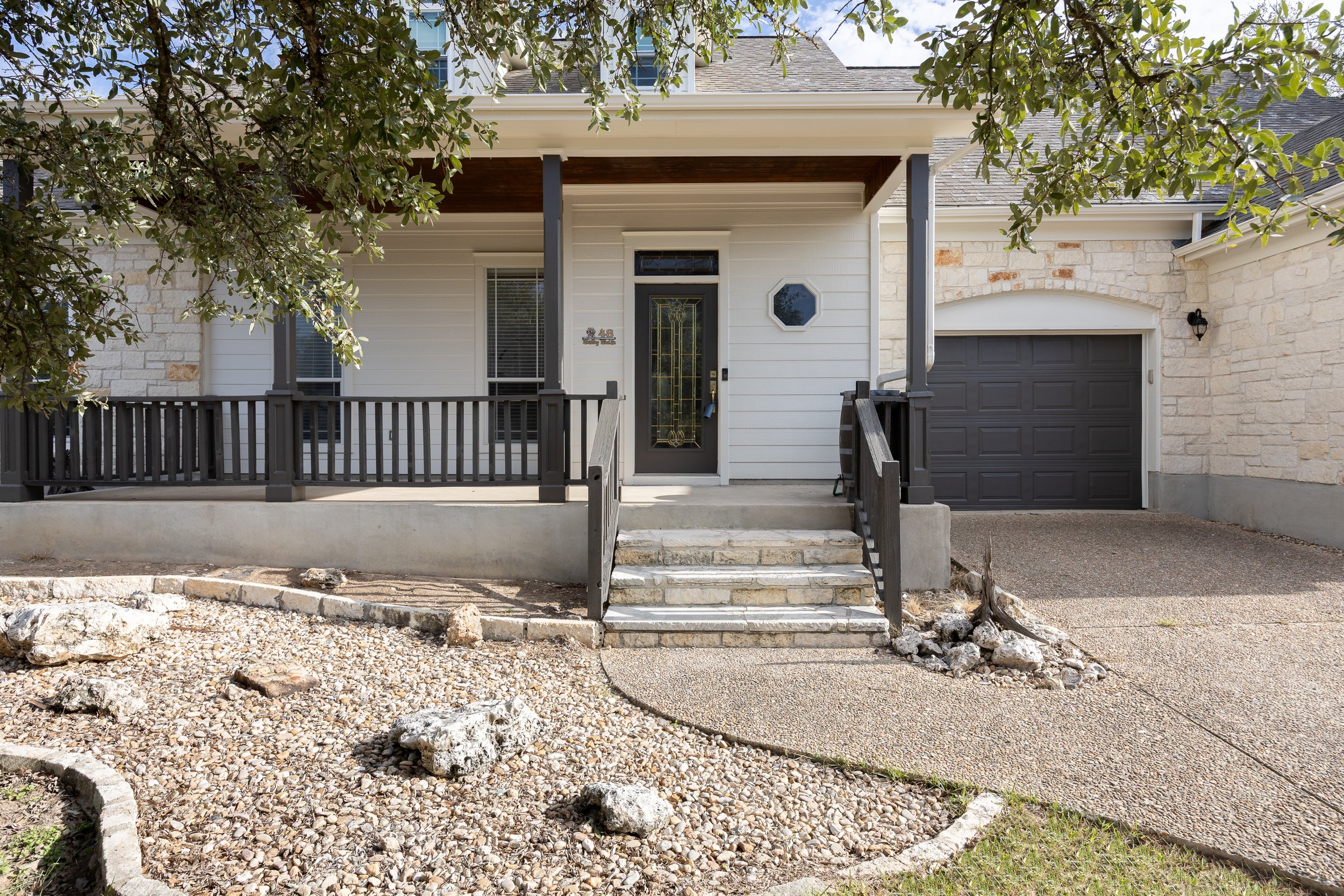 This Hill Country native limestone 2-story home has a fresh, recently painted exterior, a spacious covered front porch, and an attached two-car garage