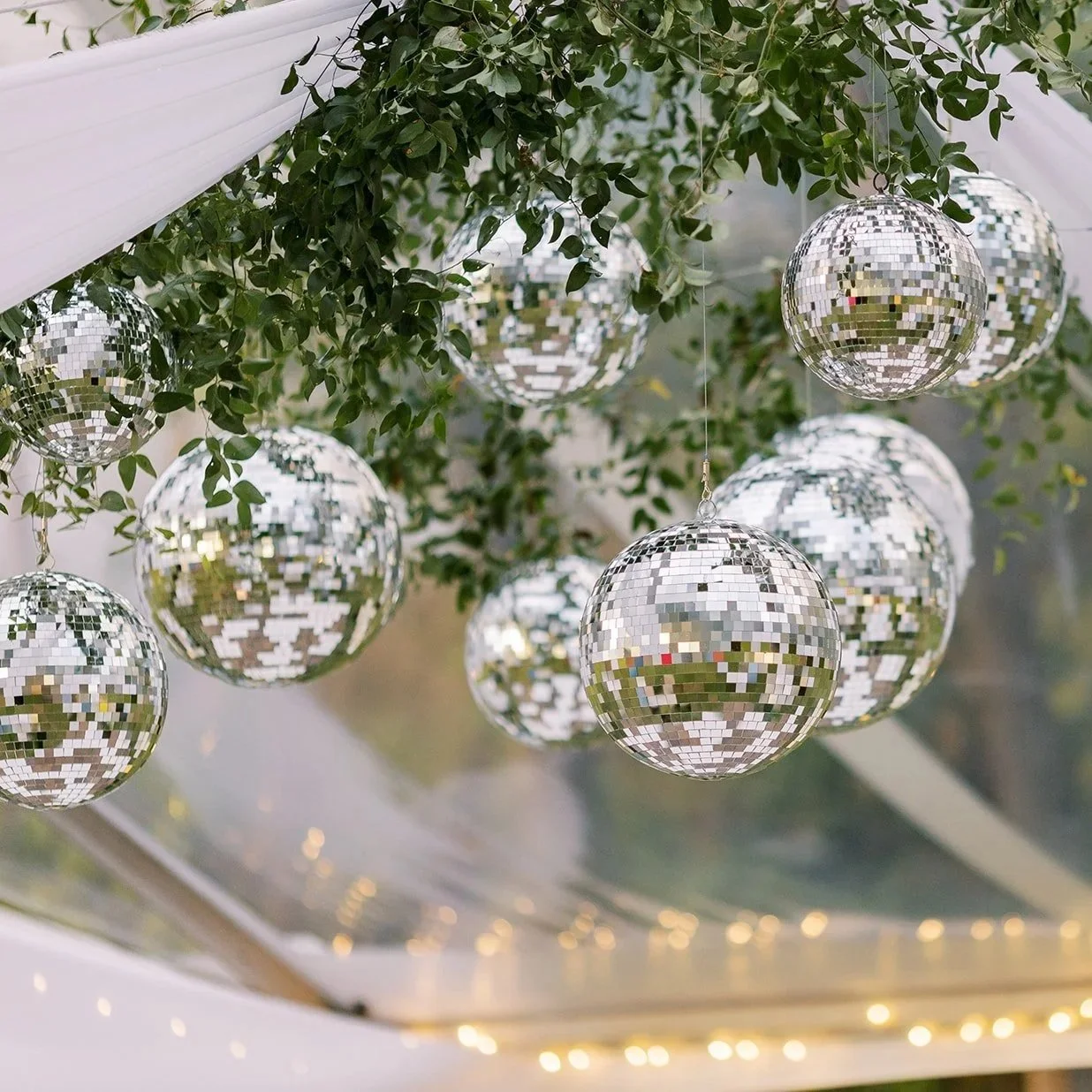 Hanging disco balls and soft draped fabric used as decorative details for an outdoor wedding celebration.