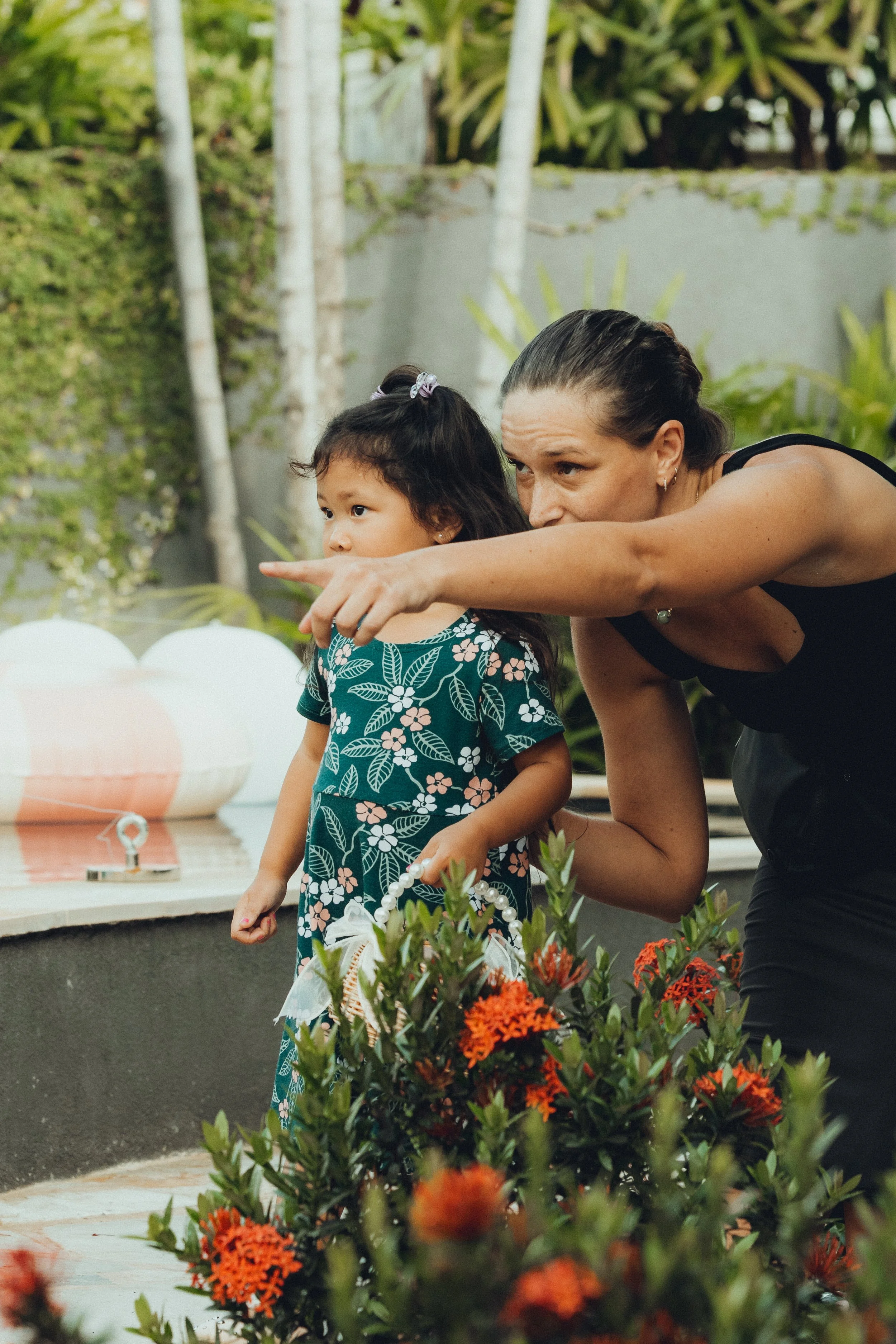 Wedding planner pointing something out to a young child during an outdoor celebration.