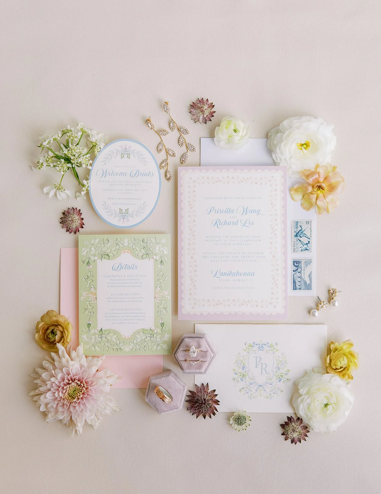 Elegant wedding invitation suite arranged with flowers, rings, stamps, and decorative details.