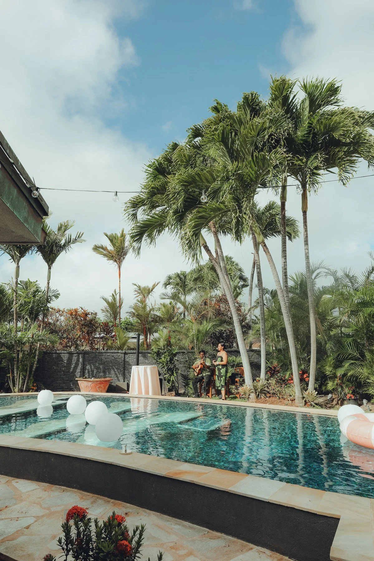 Backyard wedding setting with palm trees and floating white decorations in the pool.