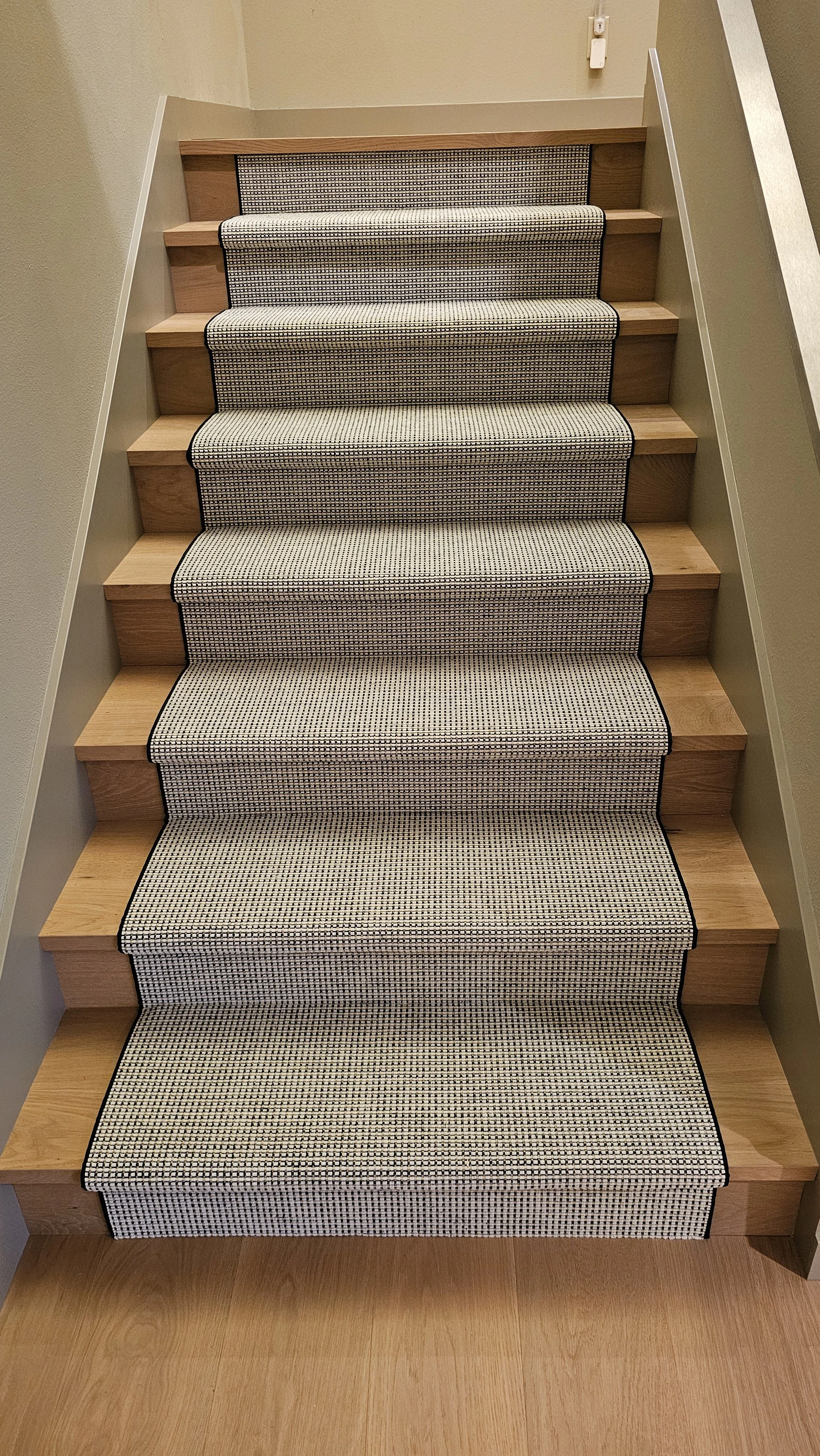 Wooden staircase with a black and white checkered carpet runner.