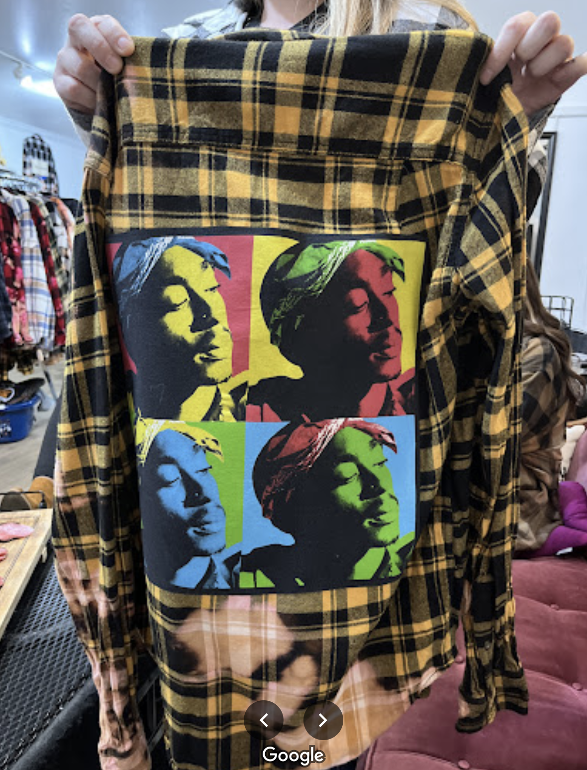 A person holding a plaid shirt with a colorful pop art graphic of a woman's face in four different color schemes.