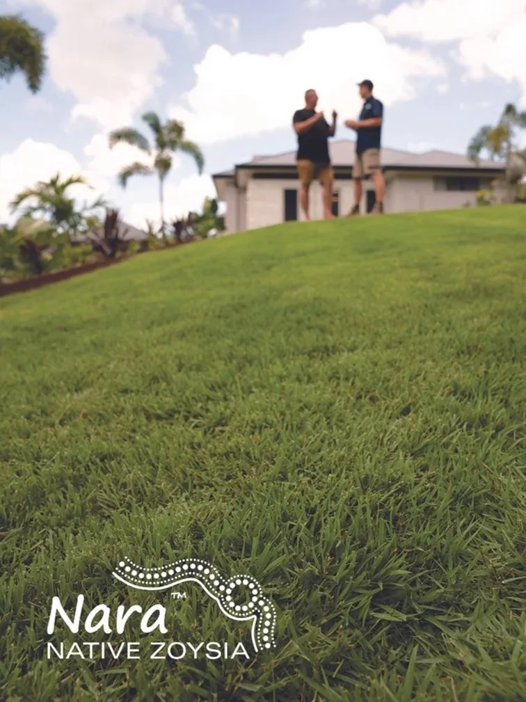 Two people are standing on a grassy hill in front of a house, having a conversation. The sky is partly cloudy with some trees in the background. In the lower left corner, there is a logo that says "Nara Native Zoysia" with a serpent design.