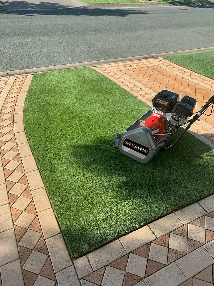 A grass patch being installed on a patio using a surface machine.