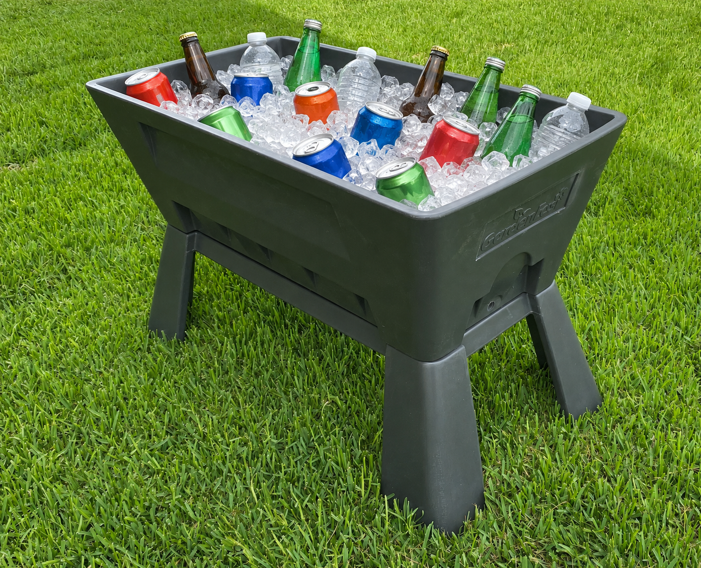 A black plastic cooler filled with ice and assorted cans and bottles of soda placed on a green grassy lawn.
